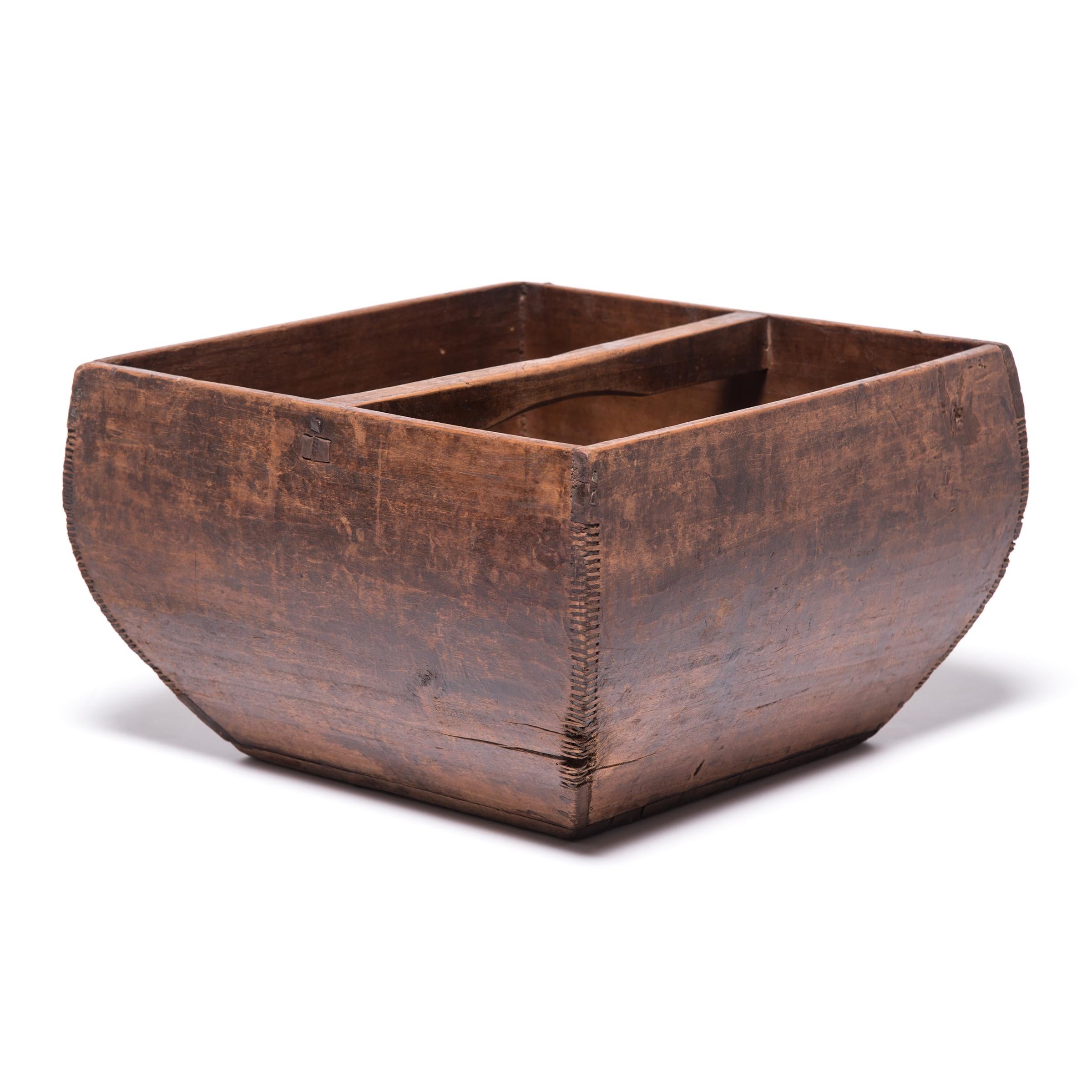 This rustic container was made over a hundred years ago to measure and hold a dou of rice, an ancient Chinese measurement. Hand-crafted of pine wood, the vessel has gracefully swelling sides and a straight handle burnished from the touch of many