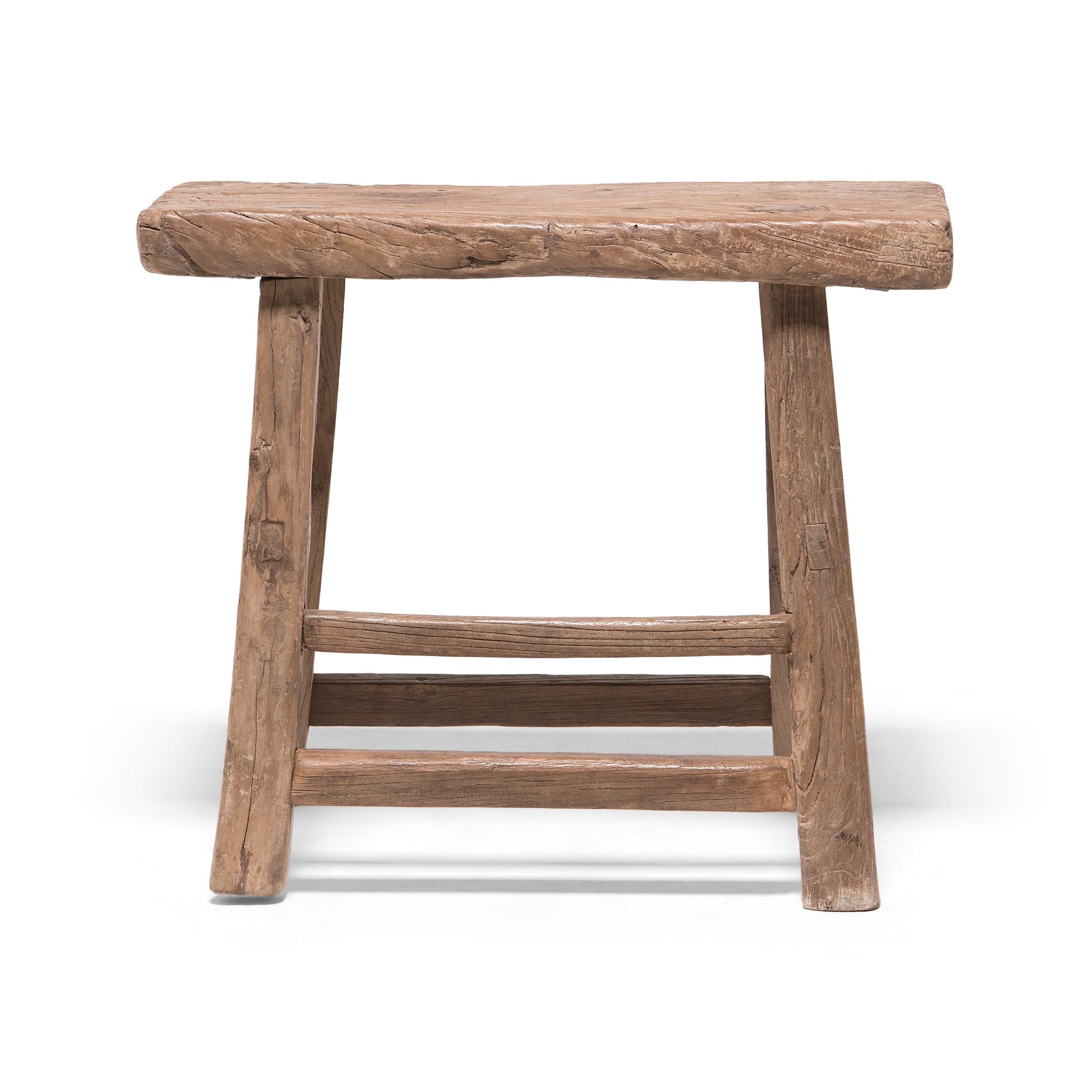 This early 20th-century stool from China's Hebei province features a wide, rectangular seat supported by splayed legs linked with simple stretcher bars. Constructed of northern elm (yumu) using mortise-and-tenon joinery techniques, without the use