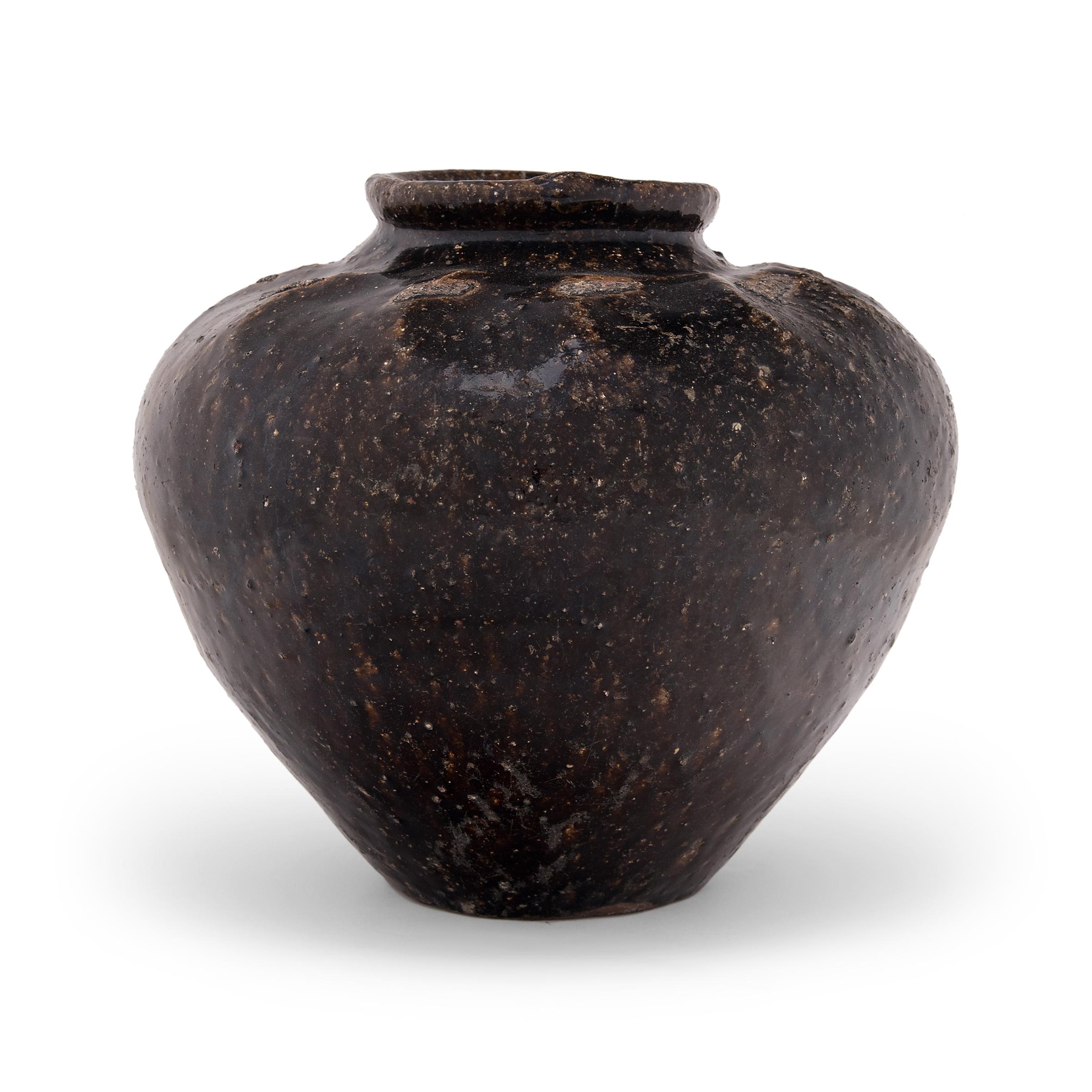 Originally used for salt pickling foods in a provincial kitchen, this early 20th century stoneware jar from southern China is coated inside and out with a dark brown glaze. The jar has a tapered form that narrows at the base and high shoulders