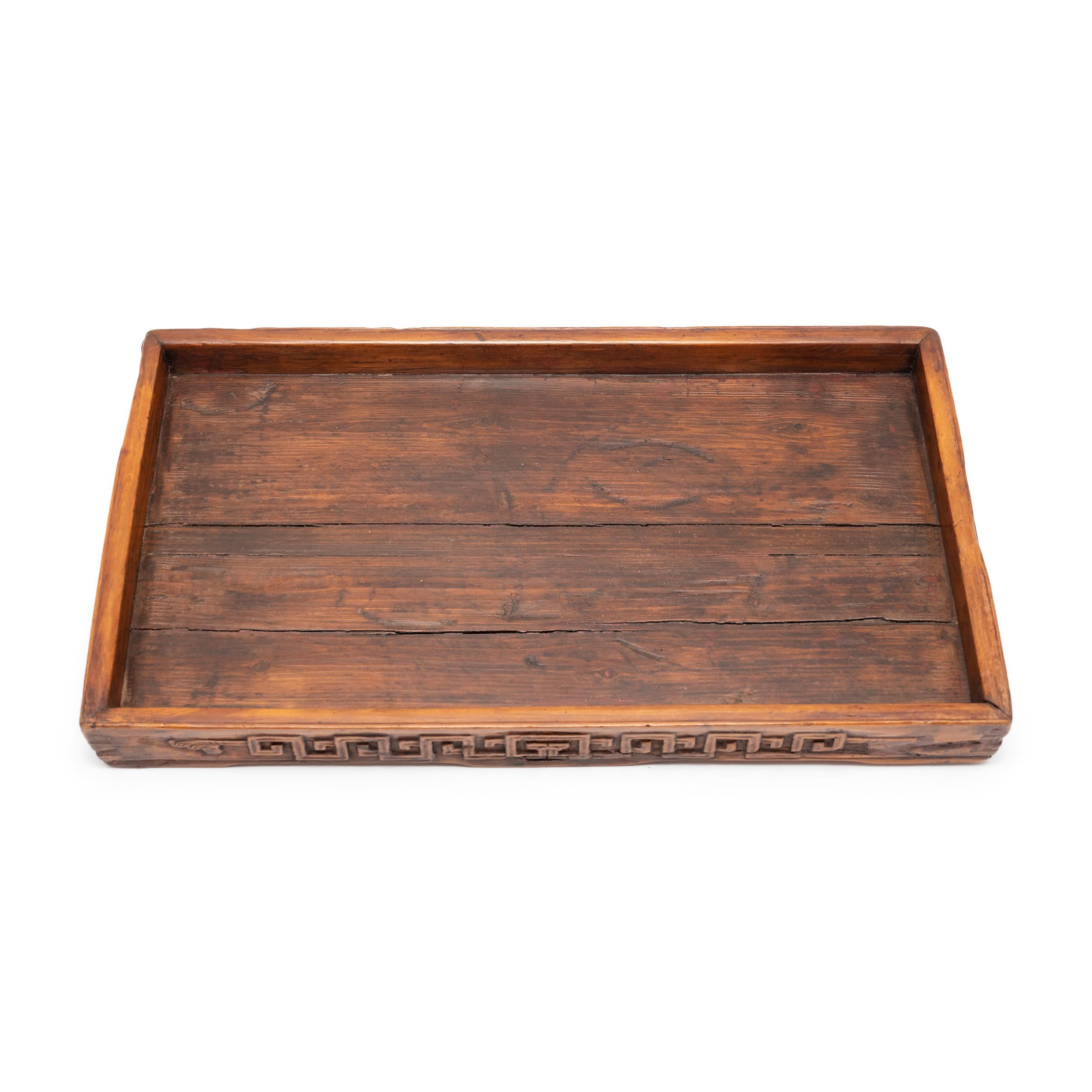 Carved geometric scrollwork and a subtly recessed base elevate the simple lines of this century-old wooden tea tray. The provincial platter has developed great character from years of serving tea, likely for friends and family gathered on