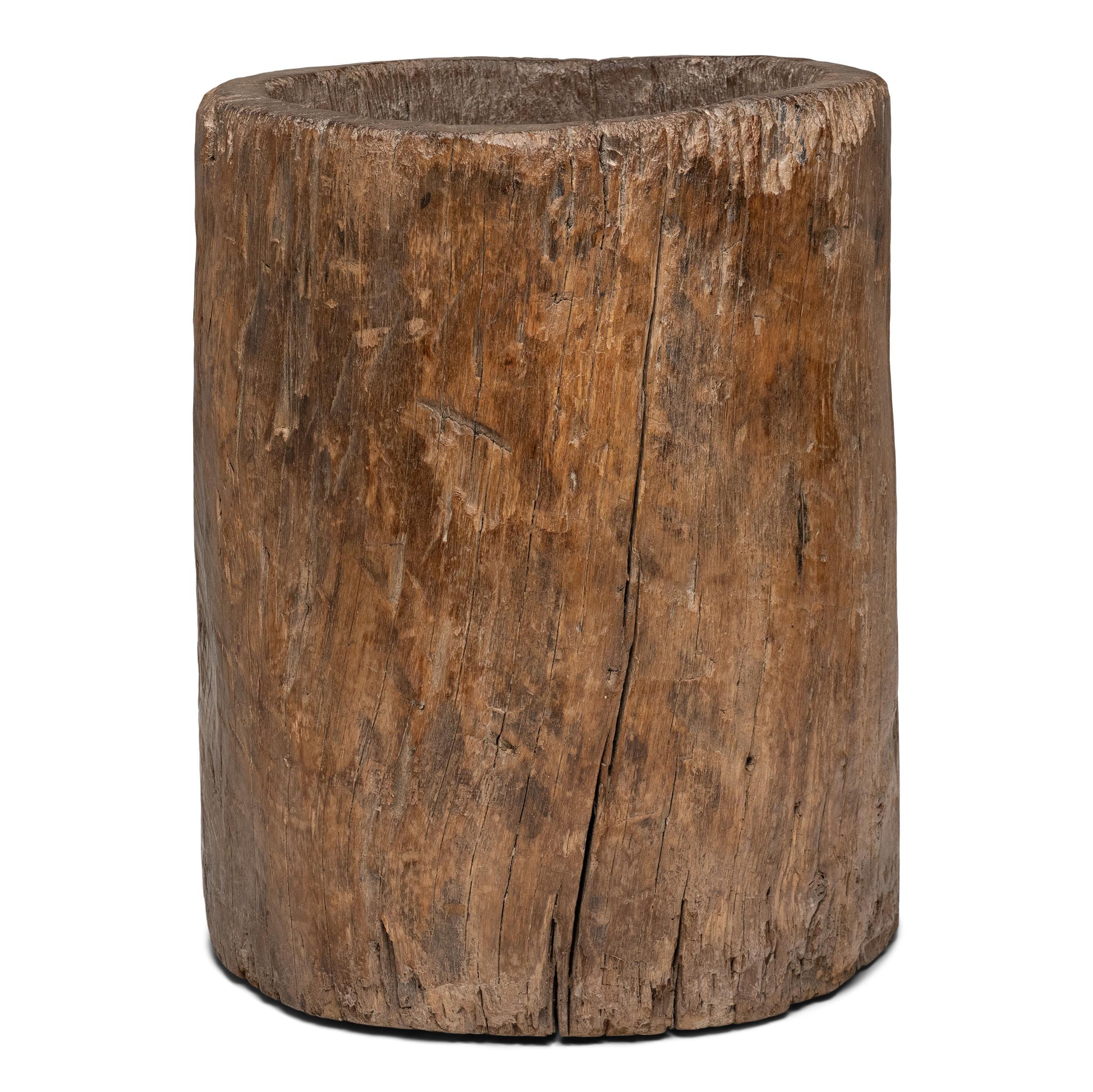 This large wooden mortar dates to the late 19th century and was originally used for crushing rice, grain, spices and other foodstuffs. Carved from a single tree trunk, the mortar has a smoothly worn interior bowl from years of use. The exterior is