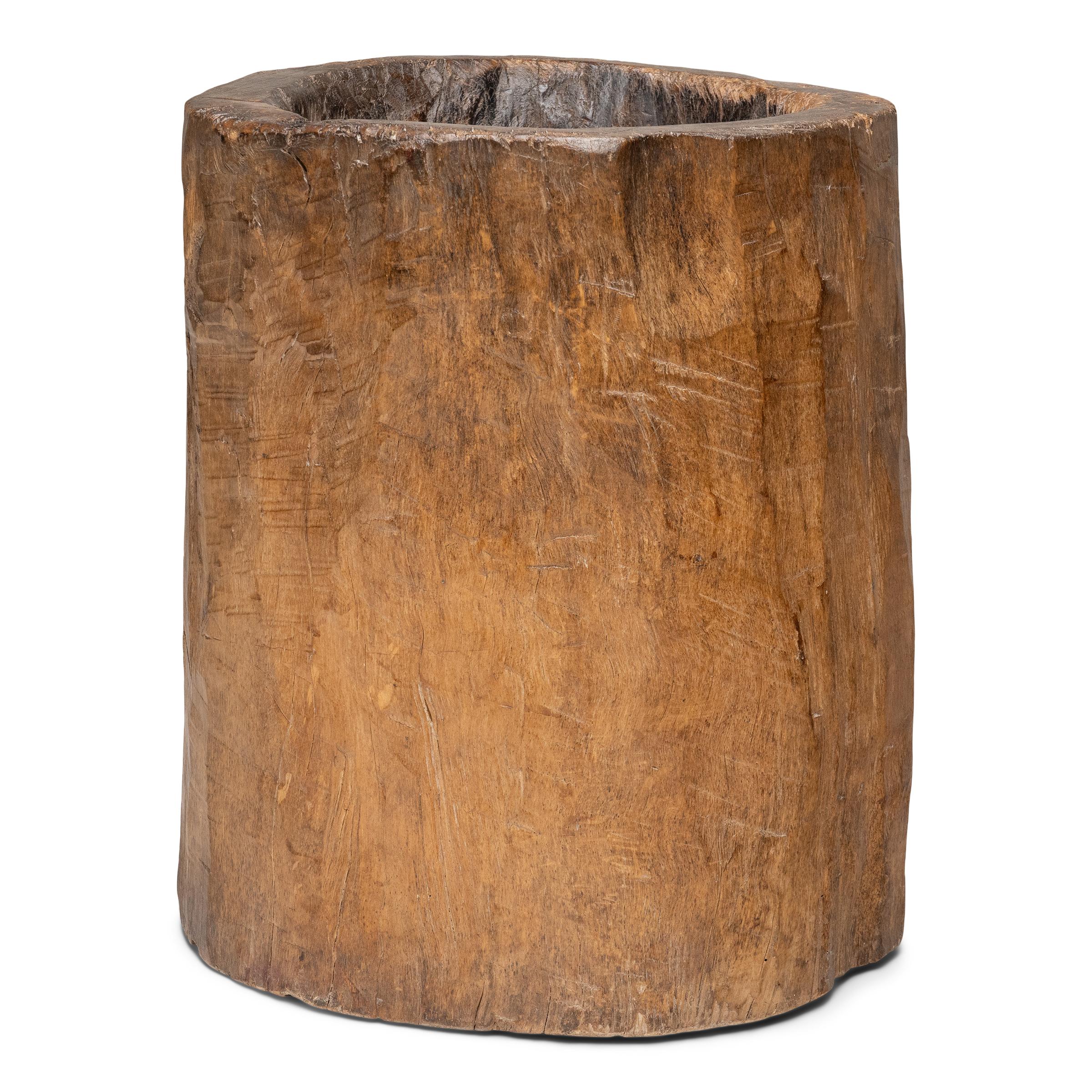 This large wooden mortar dates to the late 19th century and was originally used for crushing rice, grain, spices and other foodstuffs. Carved from a single tree trunk, the mortar has a smoothly worn interior bowl from years of use. The exterior is