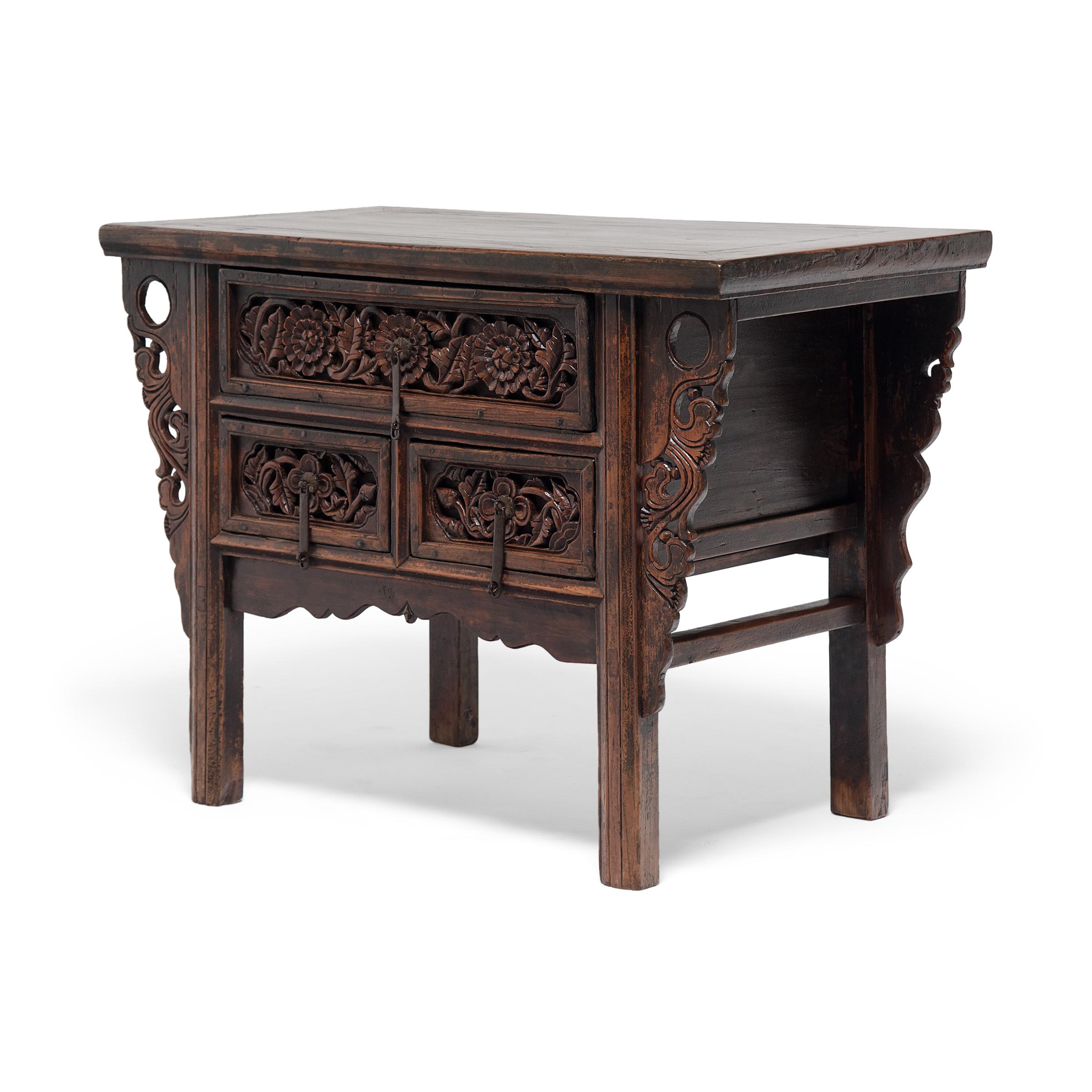Used as a family altar table or for general storage, this 19th century coffer is decorated with intricate carvings of round chrysanthemum blossoms, symbols of autumn and joviality. The table rests on straight legs that link to the rectangular table