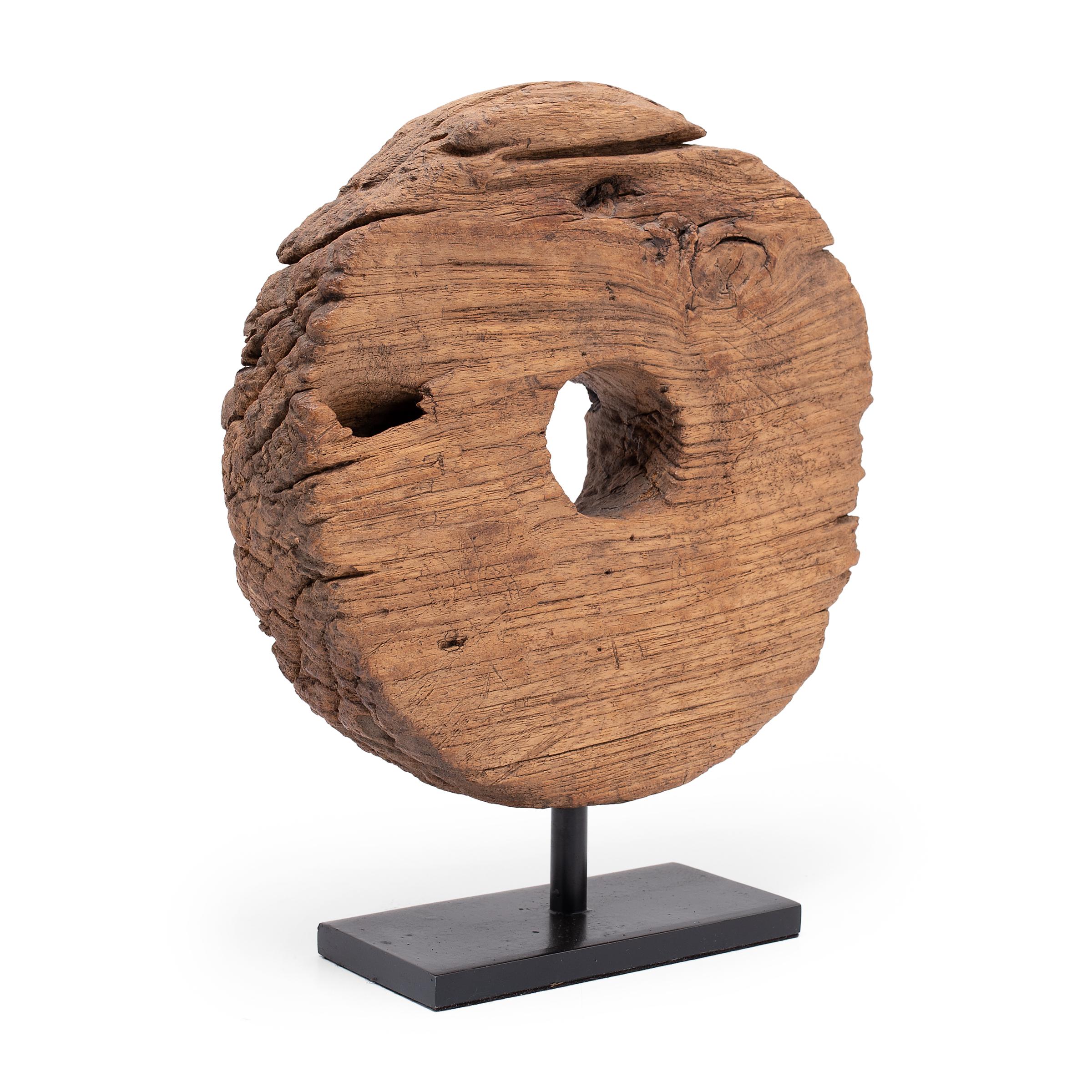 This 19th-century wooden farm cart wheel captivates with simple lines and wabi-sabi textures. The expressive grain of Chinese northern elm (yumu) is on full display, beautifully aged with deep grooves and softened by a rich patina. Elevated by a