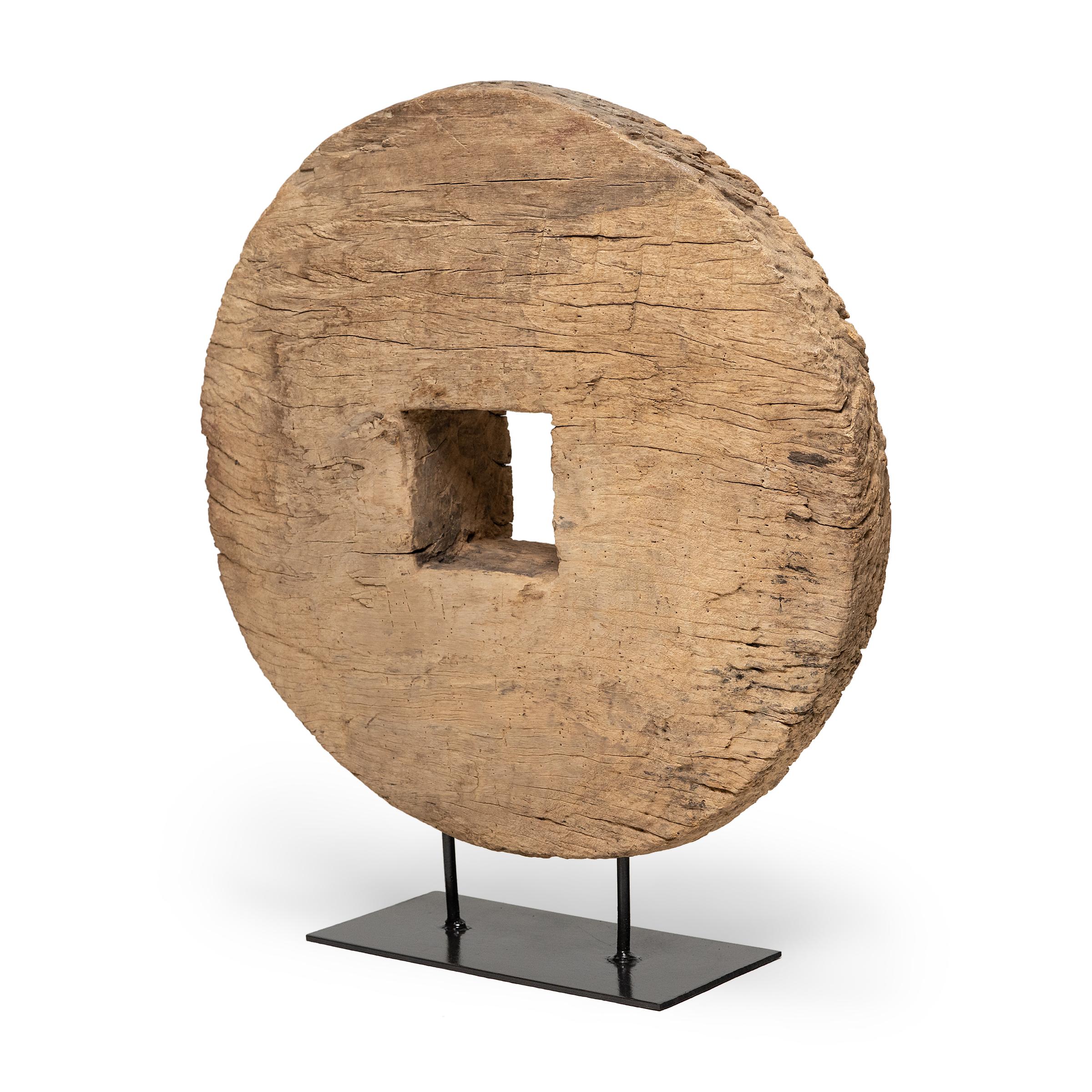 This large 19th-century wooden farm cart wheel captivates with simple lines and wabi-sabi textures. The expressive grain of Chinese northern elm (yumu) is on full display, beautifully aged with deep grooves and softened by a rich patina. Elevated by