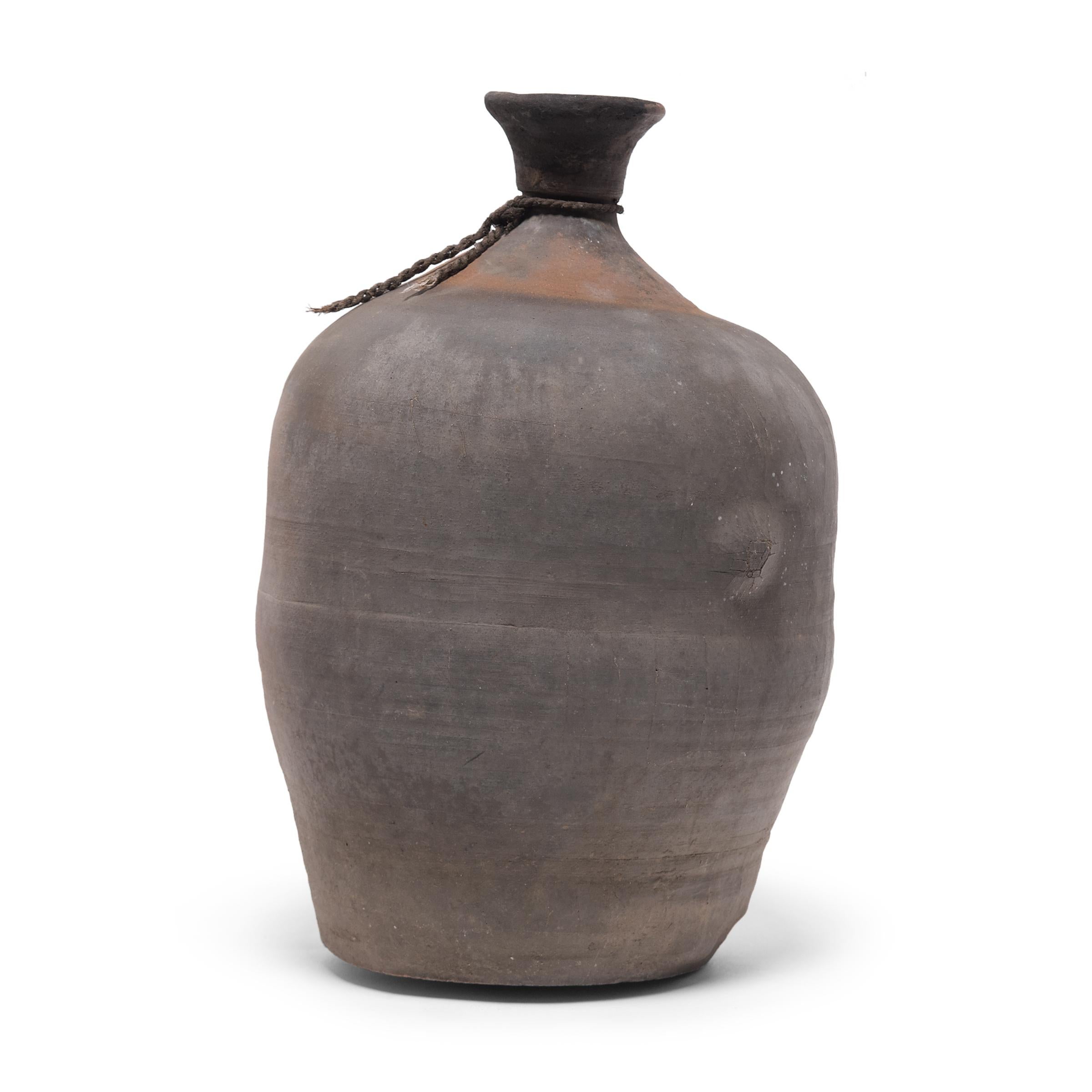 This ceramic jar from China's Shandong province has a bottle-neck shape meant for storing vinegar or wine made from rice and grain. Dated to the early 20th century, the jar was likely created to store wine for commercial sale and would have been