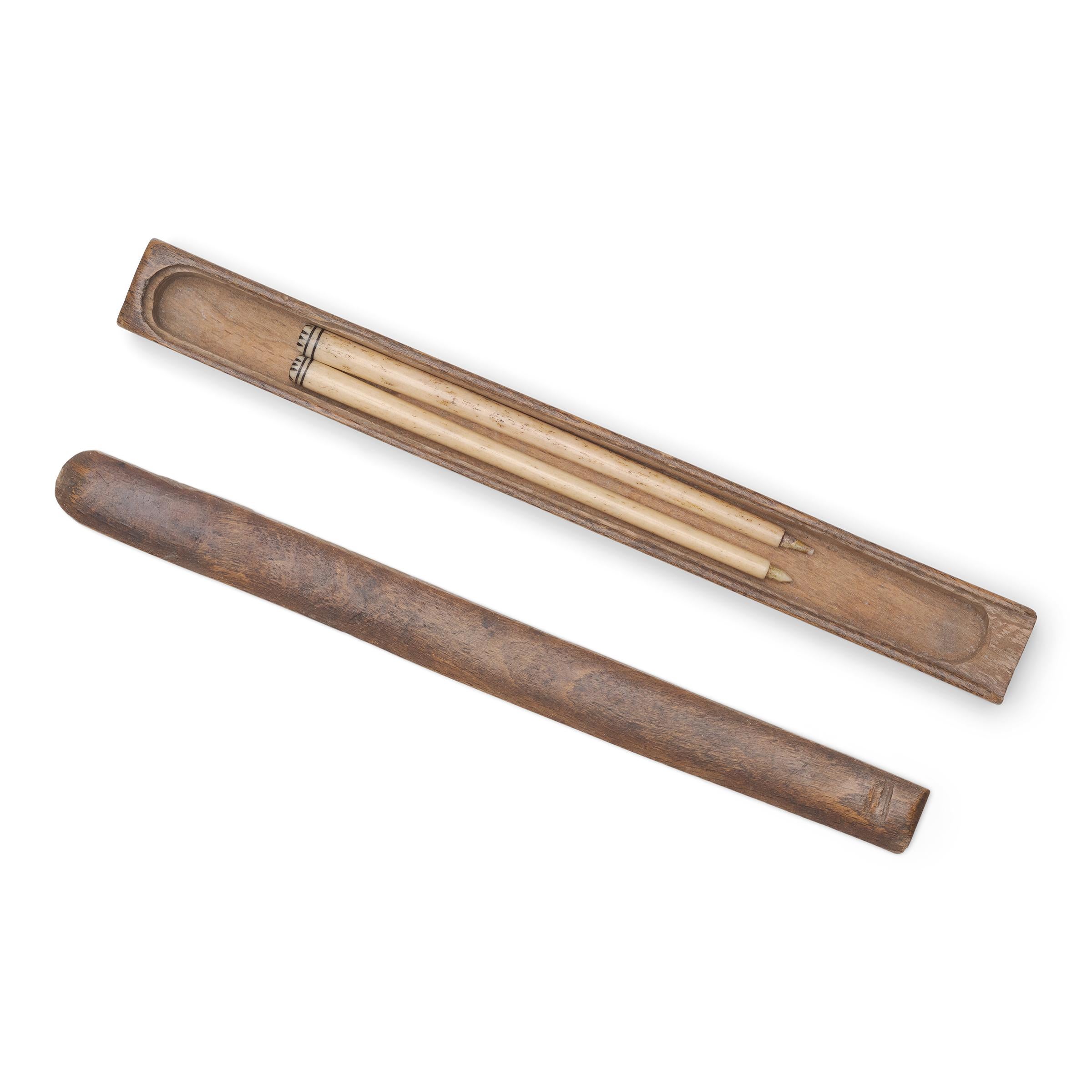 A narrow wooden box with a sliding lid and a pair of carved bone chopstick handles with contrasting dark inlay at the ends. The bone handles were likely originally affixed to chopsticks of wood or metal, the latter suggesting they would have been