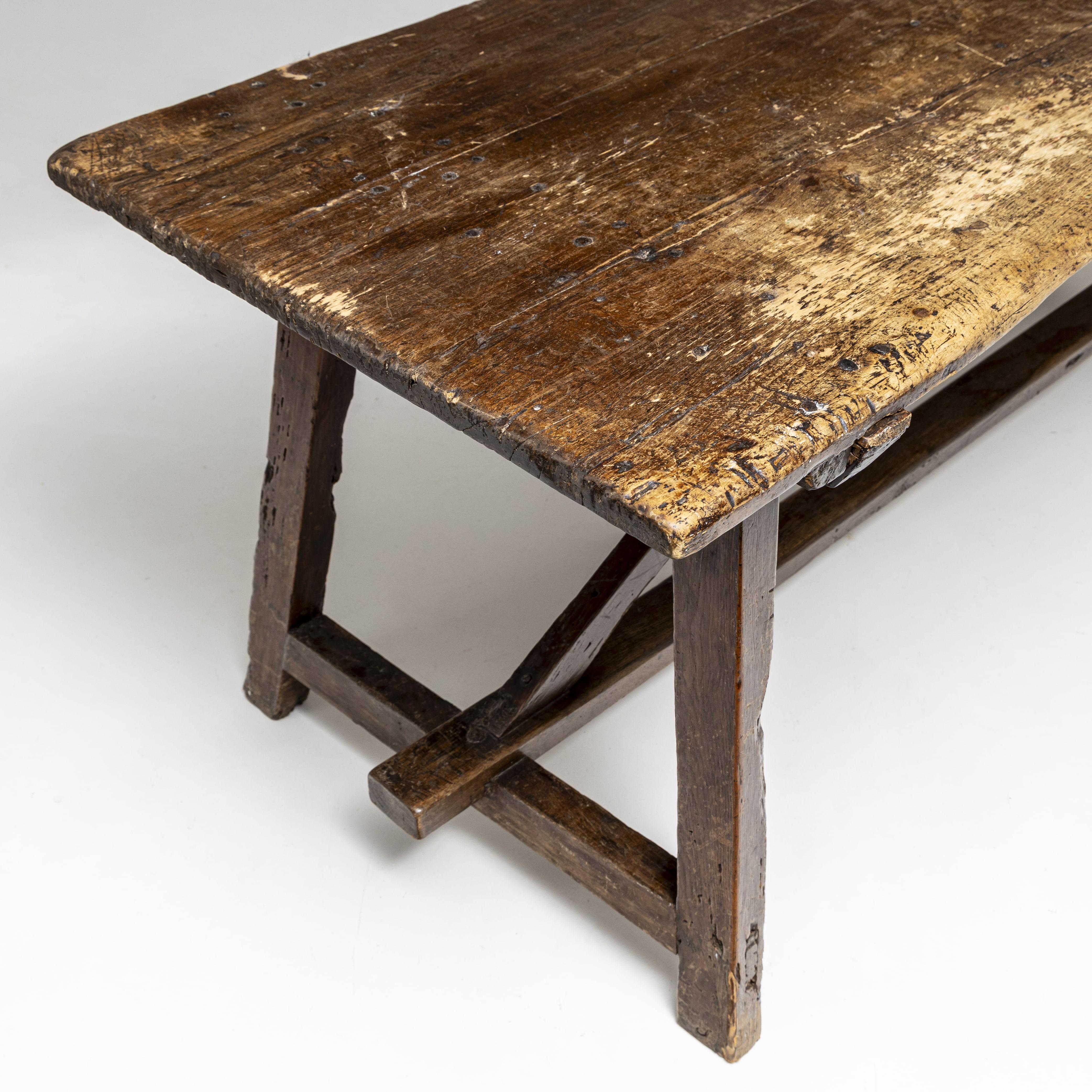 Large rustic dining table or work table made of solid pine with a central bar and strong, decorative patina.