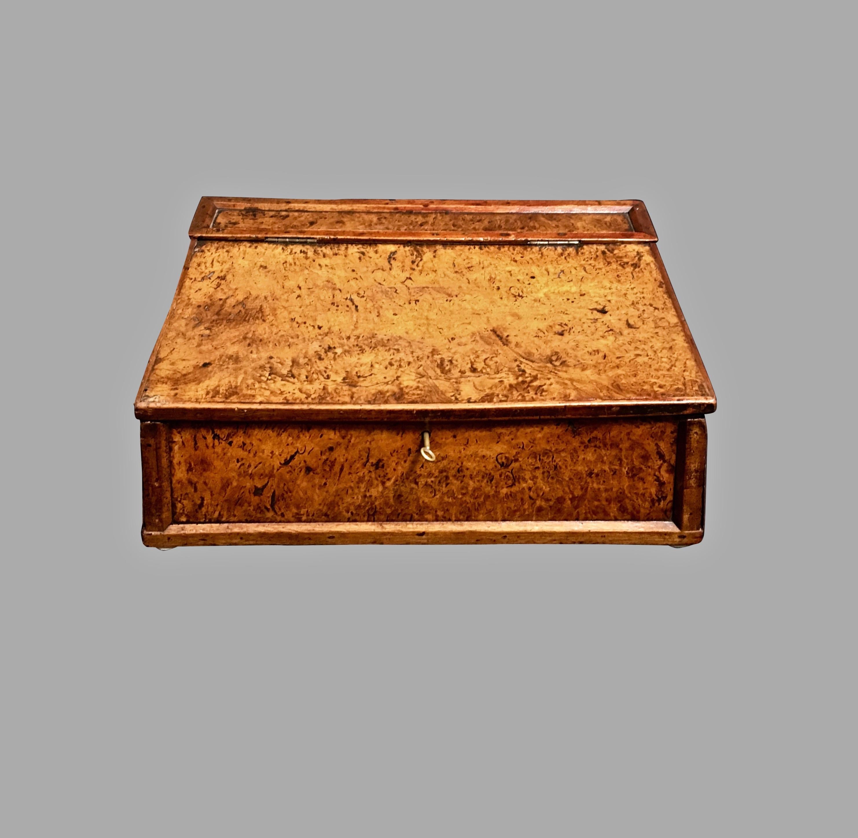 An English provincial burl elm writing slope, with a hinged lid opening to reveal a lined interior, circa 1800, with key.