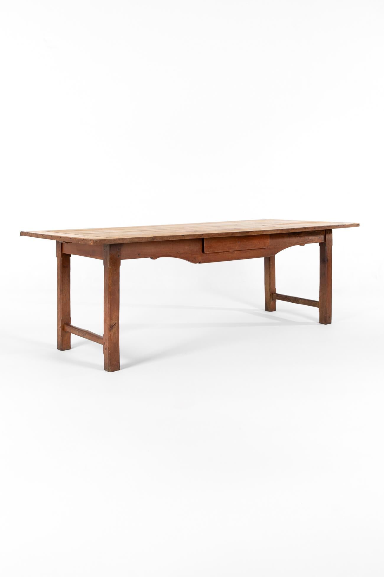 A large provincial French farmhouse table with an oak base and pine top.

The generous top is beautifully weathered with an open grain and a rich patina.

Four carved block legs with cross stretchers, peg and tenon joints,  a shapely carved apron