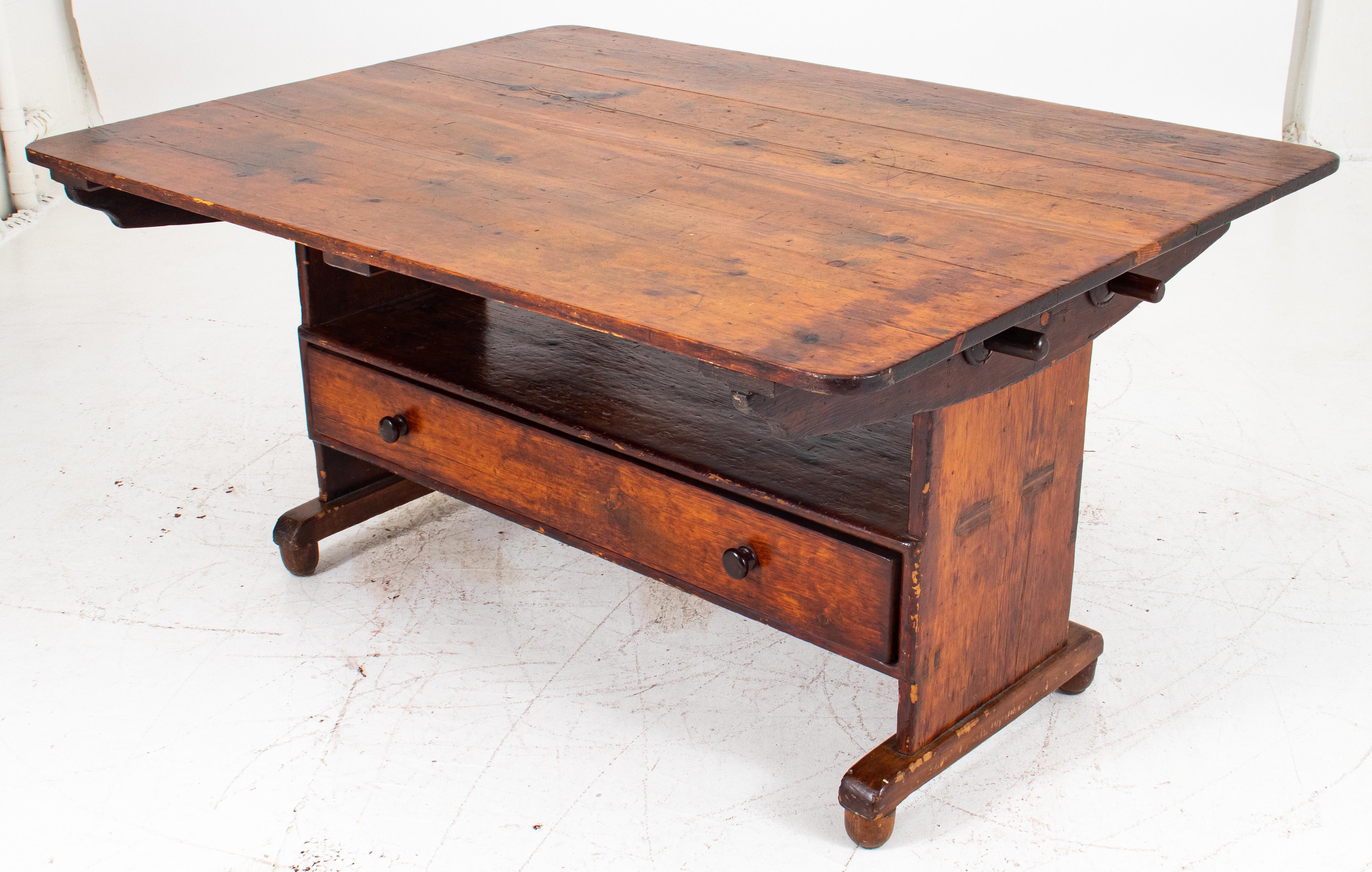 Provincial French pine tavern table-bench, 19th c., possibly Alsatian and with Helvetic influence, with removable and/or hinged top held in place by two dowels, lifting to reveal a bench above a long drawer for storage on half-rounded feet. 30