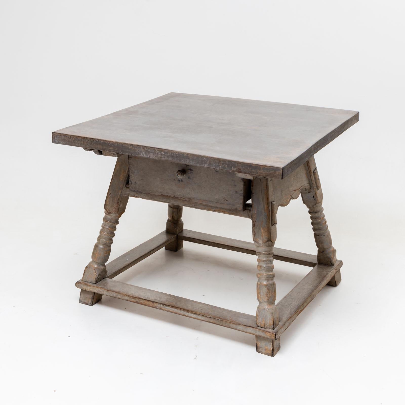 Table centrale provinciale avec plateau rectangulaire et repose-pieds. Un grand tiroir profond se trouve sous le plateau de la table. La peinture grise est neuve et présente une patine antique. 