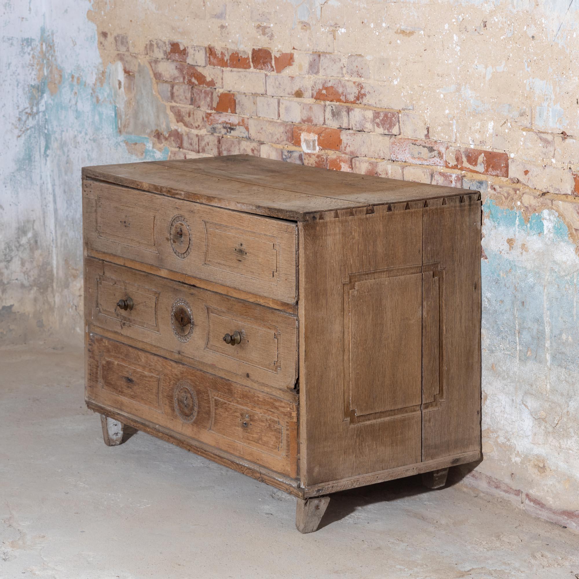 Provincial Louis Seize chest of drawers with three drawers and decorative panels on the front and sides. The chest of drawers is made of solid oak and is in an unrestored condition.