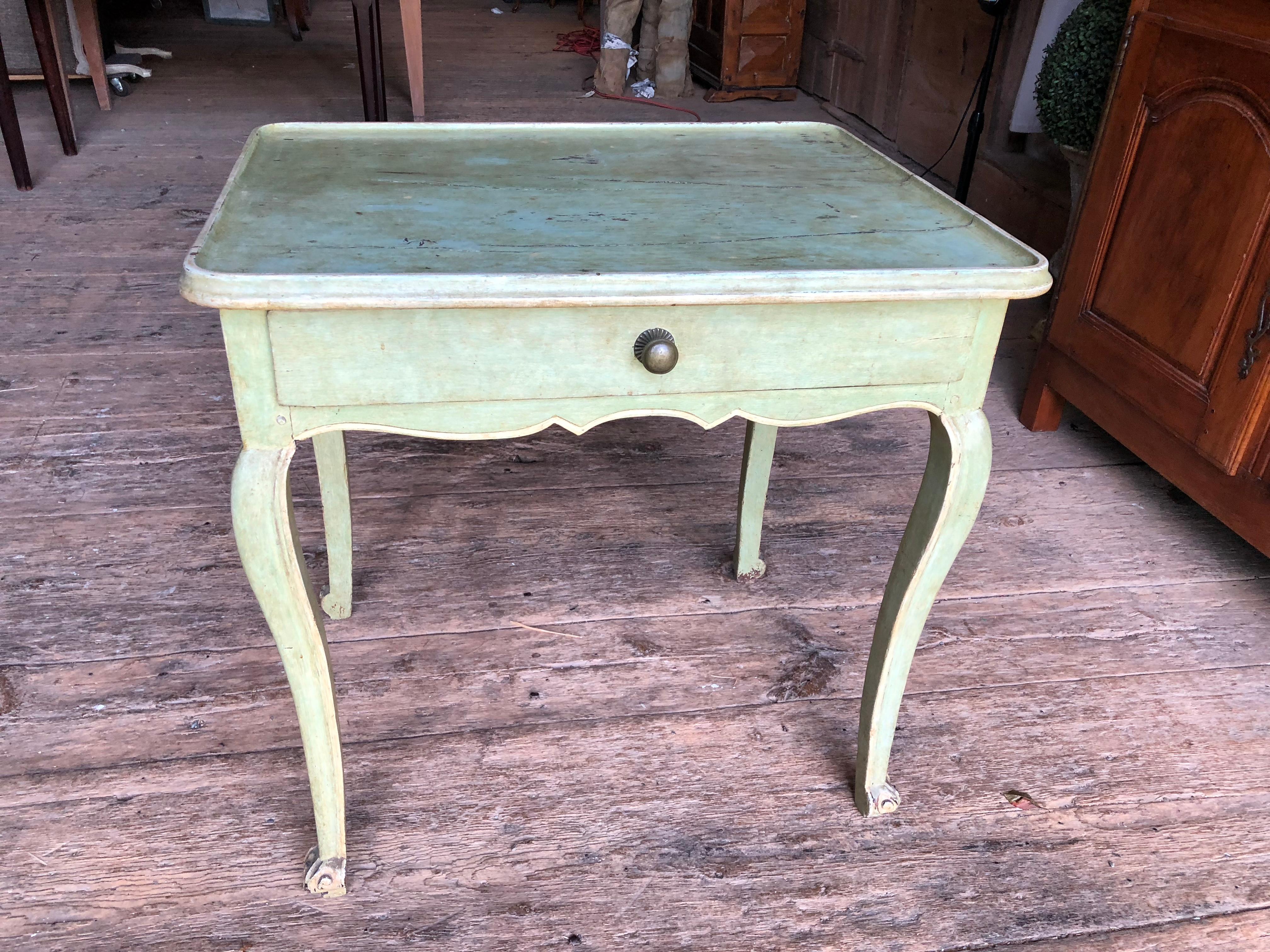 A charming Louis XV period painted side table in celedon green painted finish and cream details, French, circa 1770, with a single drawer, a dished-out top, scaloped apron and cabriole legs.