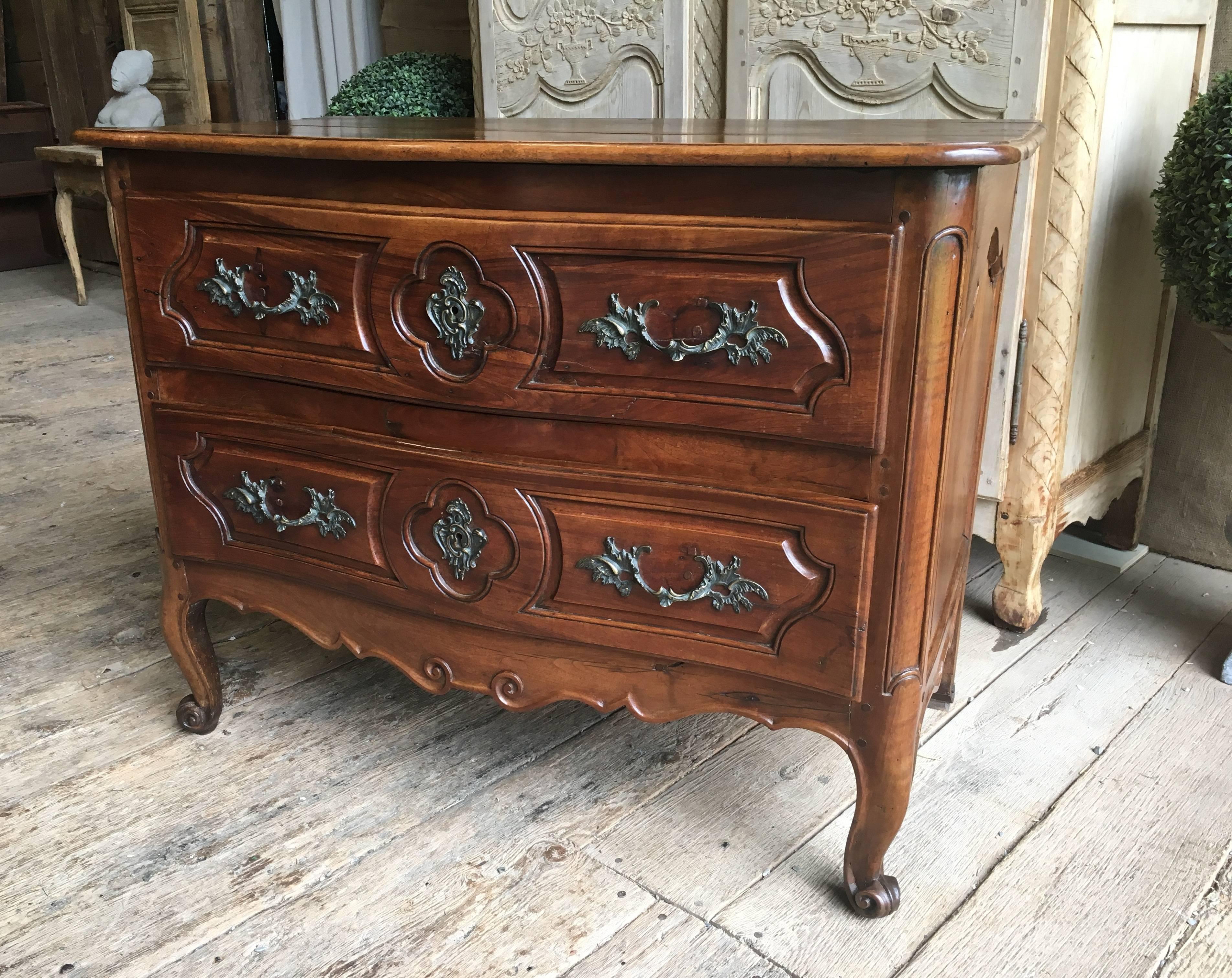 A charming two-drawer Provincial commode in walnut, circa 1760 with a serpentine top and case, nicely carved drawers and scalloped apron on cabriole legs with escargot feet. South of France.