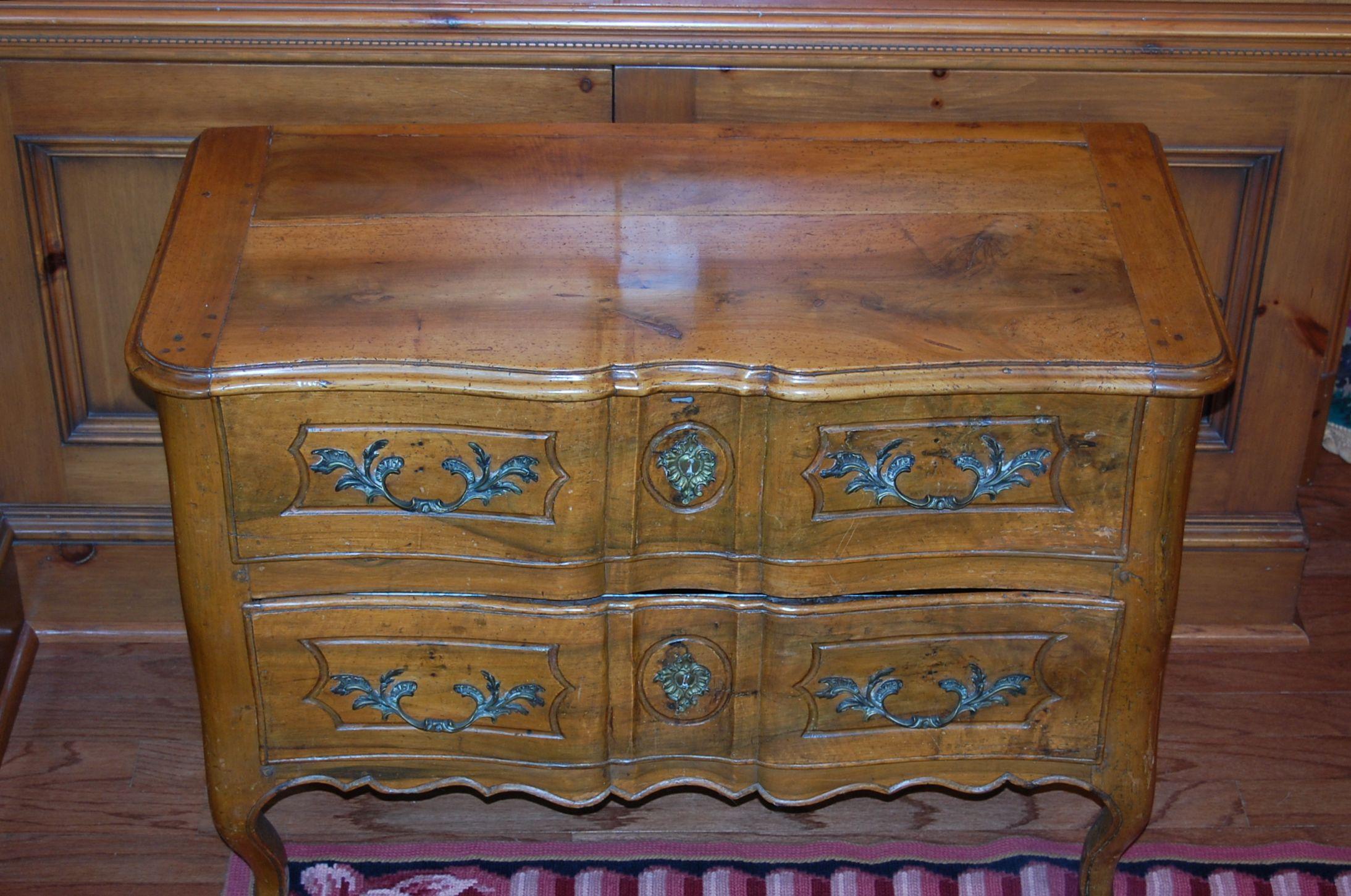 A provincial Louis XV period carved Walnut two drawer commode, circa 1765-1780 with original finish and delicate carvings. Original hardware. Lined in a cotton print fabric. This is a meticulously hand carved, antique French commode sauteuse from