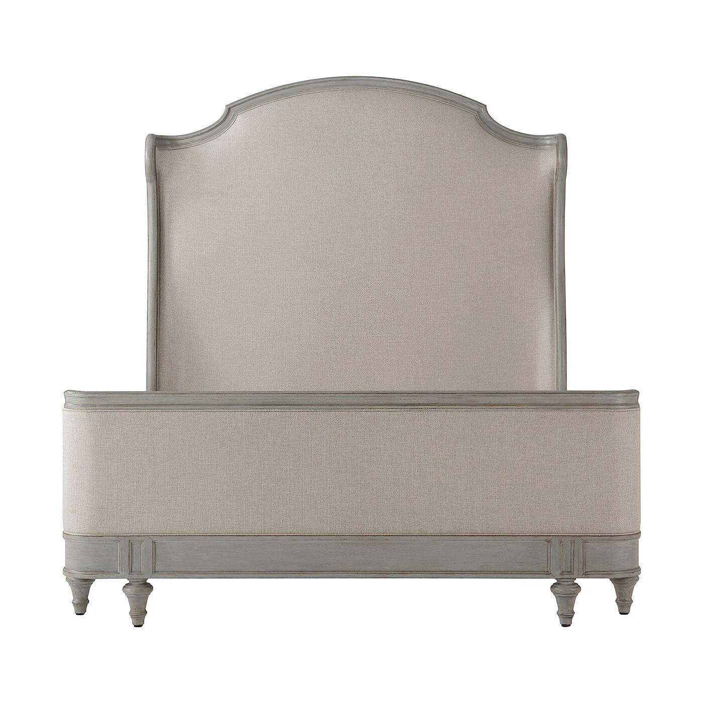 A French Provincial carved and painted Queen Size bed with an arched and molded upholstered headboard with scroll wings, an upholstered and hand-carved framed low footboard and paneled rails on turned and tapered taupee feet. 
Dimensions: 66