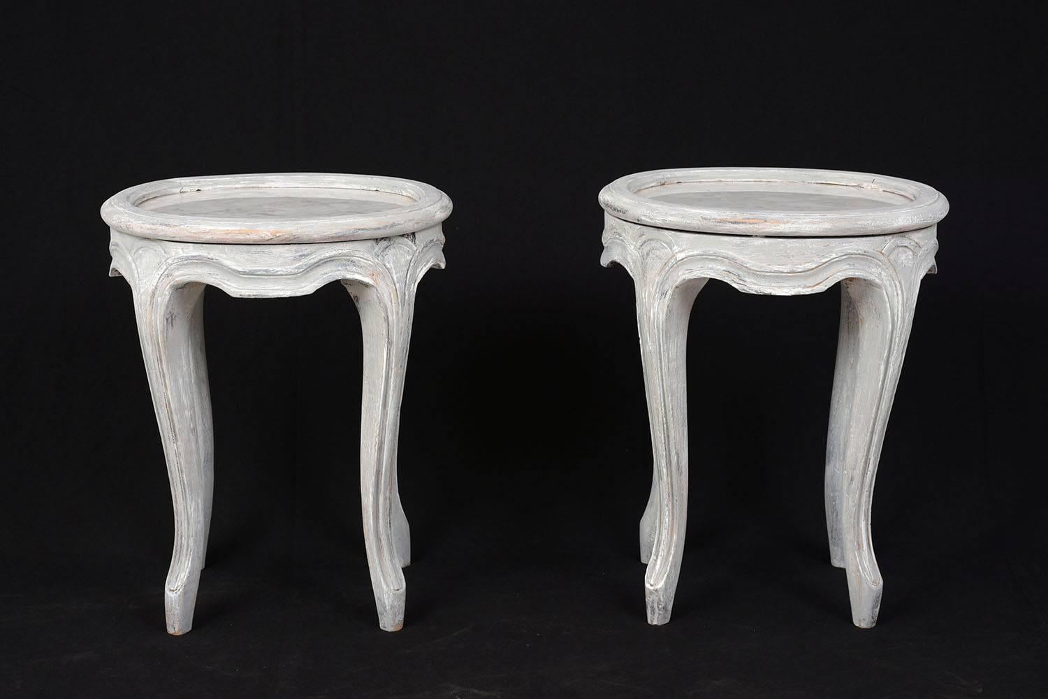 This pair of 1900s Provincial-style garden stools are made of carved oak wood painted in a gray and off-white color combination with a distressed finish. The stools have carved moulding accents and cabriole legs with padded feet. There is white