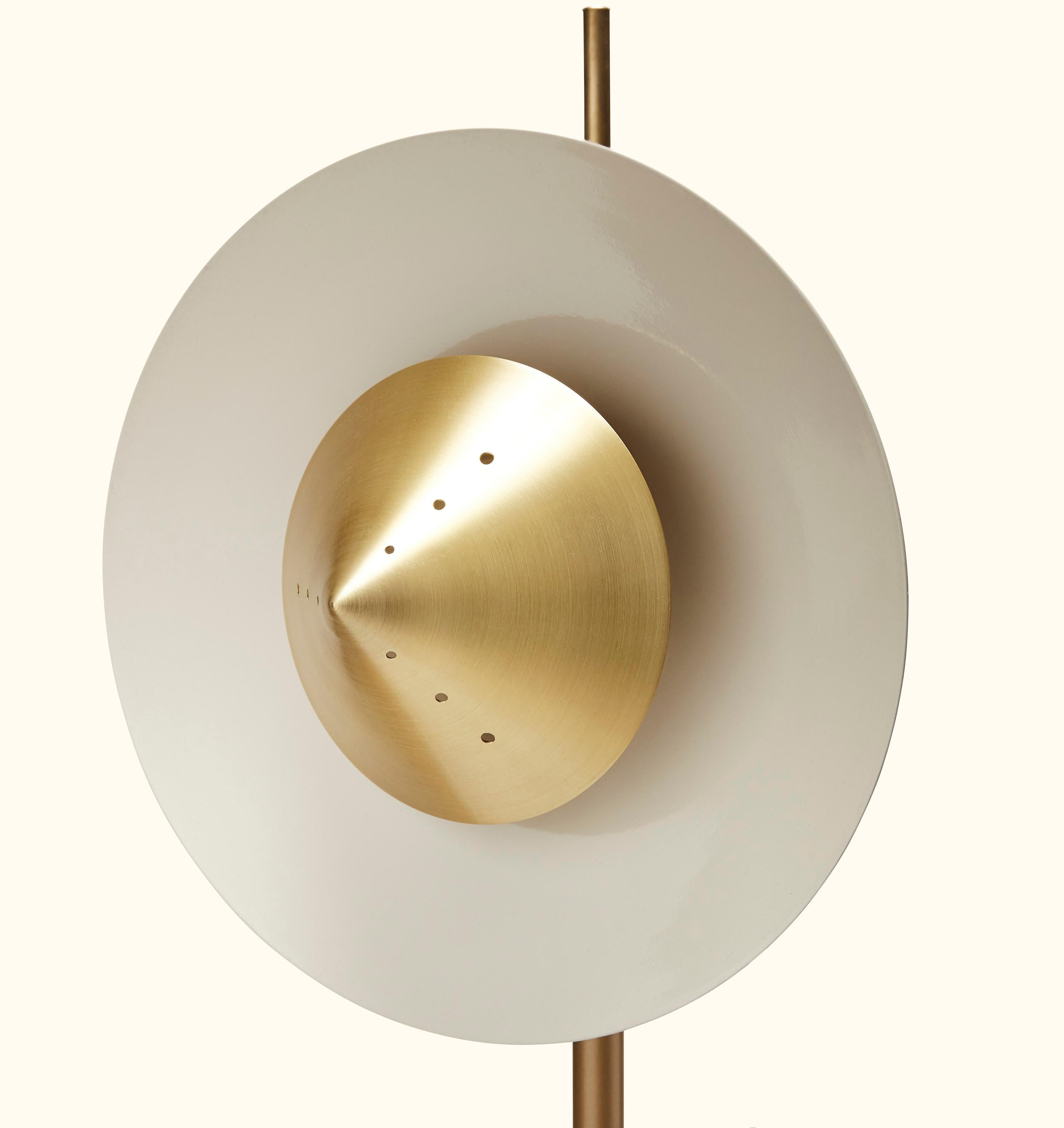 The Pruckel floor lamp features a circular spun metal shade with a perforated brass cone and turned white oak or American walnut base. The shade is adjustable and can be fastened at any desired height.