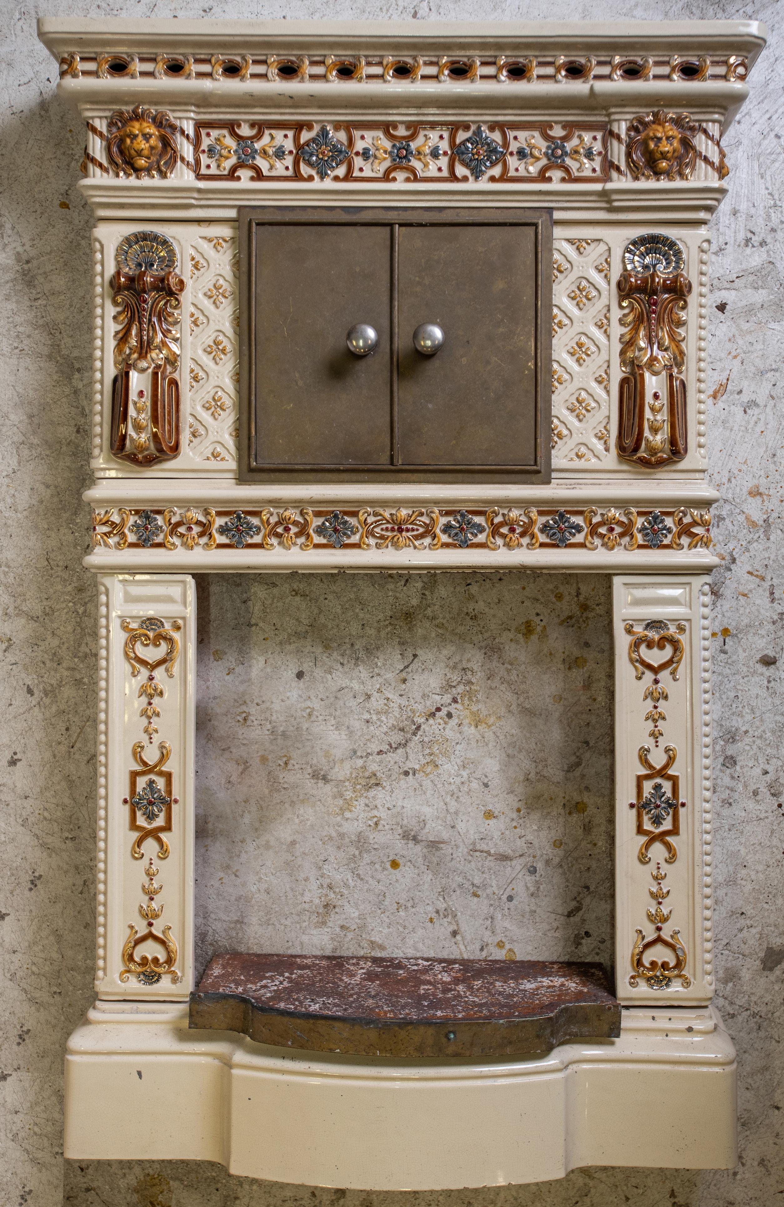 Beautiful Prussian fireplace in Sarreguemines enameled earthenware, with enamelled decoration of flowers, arabesques and lion's muzzle. 
With a hearth base made of cast iron.
The warming doors are made of brass. 

Measures: Height: 54.14