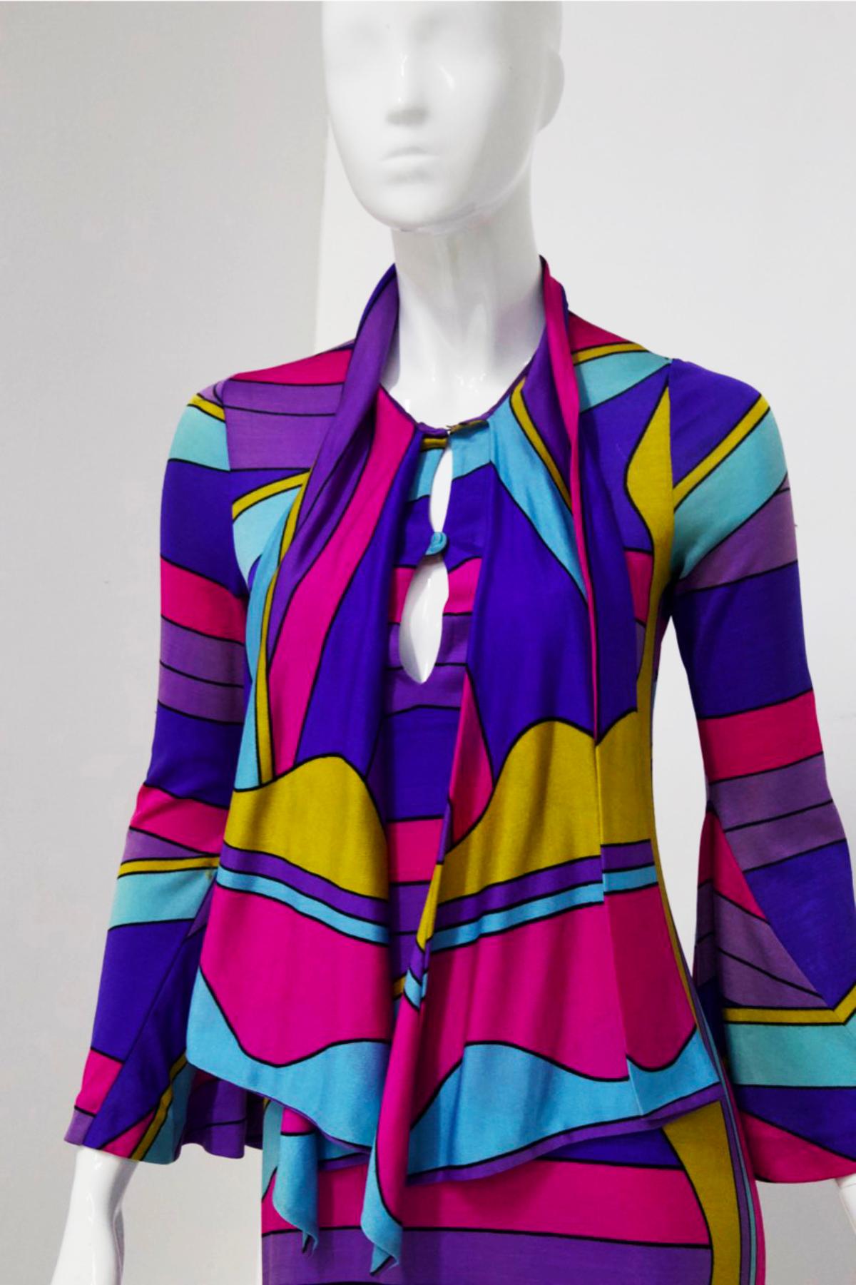 This exceptional Louis Féraud maxi dress from the late 1960s or early 1970s is made of the typical fine, lightweight synthetic fabric and features a bold psychedelic print in yellow, pink, light blue and purple on a blue background. The 