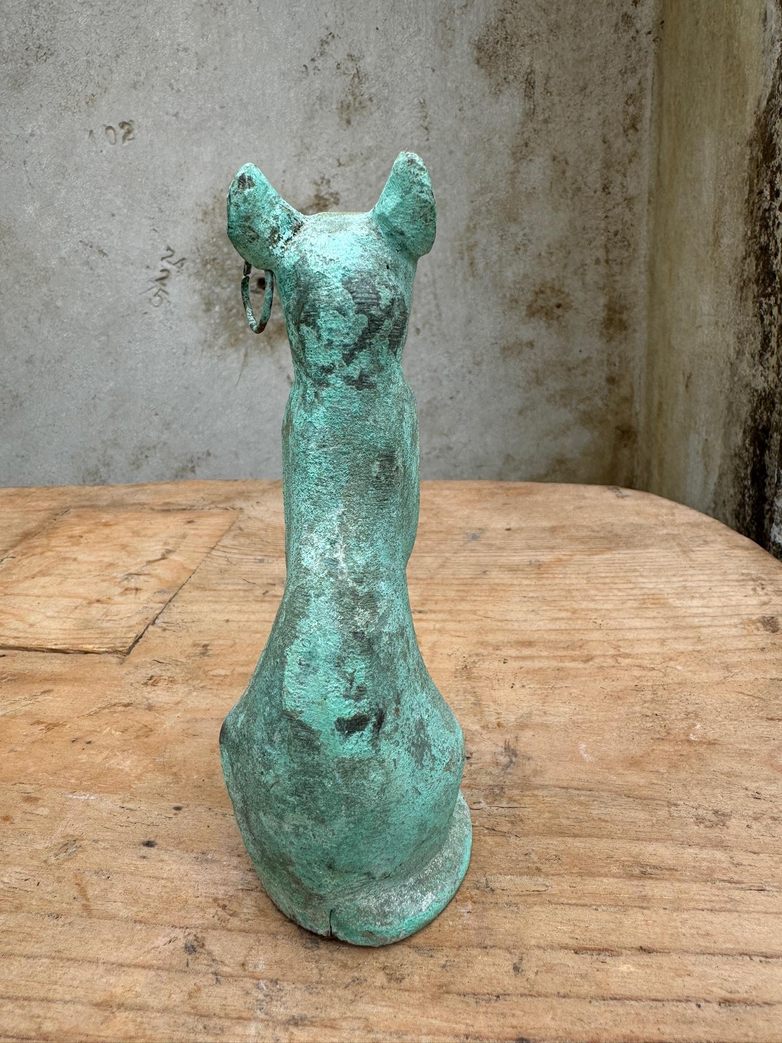 Esta escultura de gato egipcio de bronce es una obra de arte patinada que refleja la antigua tradición egipcia de veneración a los gatos. Esta escultura, que data de finales del periodo ptolemaico, representa a la diosa Bastet, asociada al hogar, la