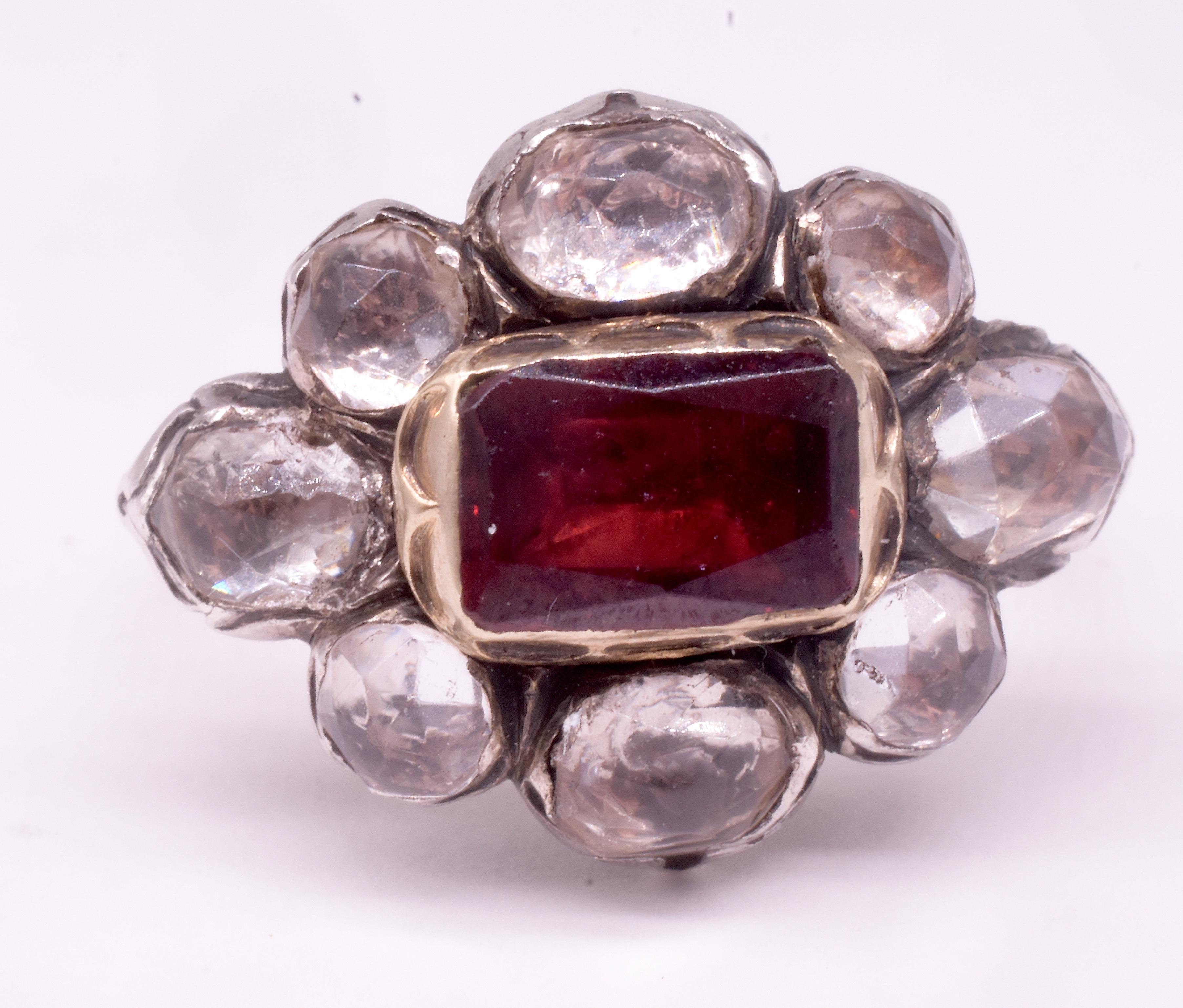 Unusual English Stuart period paste cluster ring with 8 rose cut pastes set in silver and backed in 18K with a gold bordered almandine garnet stone at center. Rings with paste stones in combination with real stones are unusual. 

The rose cut pastes
