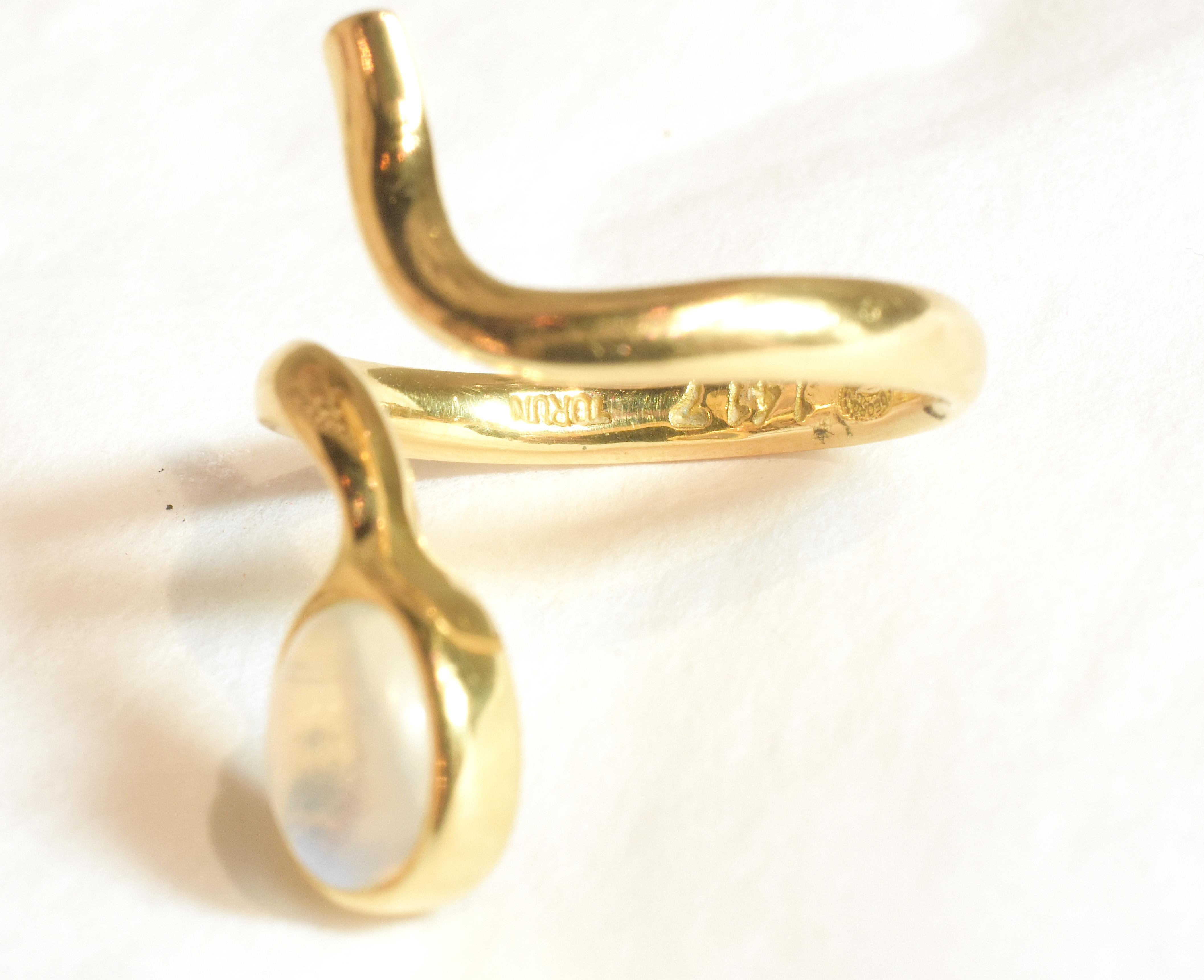 Questo anello d'oro retrò con una pietra di luna è contrassegnato dalla scritta TORUN e si riferisce a Vivianna Torun Bulow Hube, che ha collaborato con l'azienda scandinava Georg Jensen per molti anni a partire dal 1970. L'anello è contrassegnato