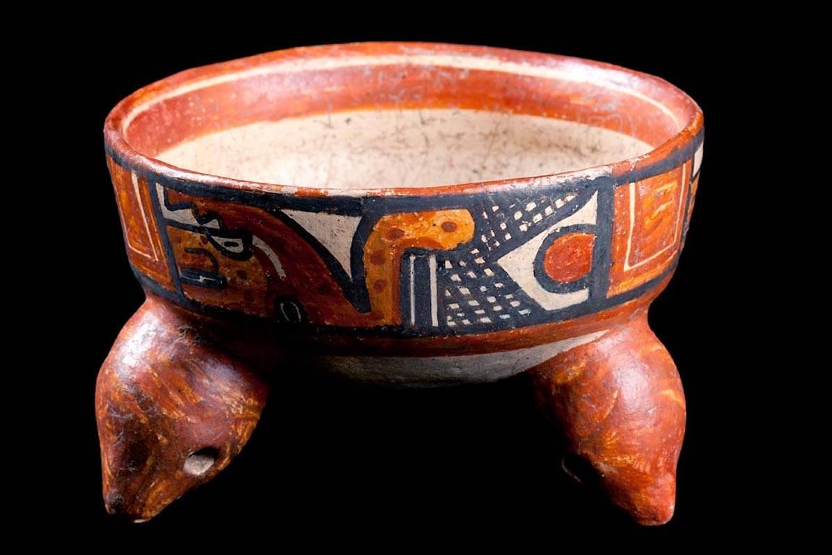 Papagayo polychrome pottery bowl, Mandador variety. Round bottomed bowl rests on three animal headed rattle legs. Exterior painted wide band with two stylized plumed serpents of jaguars with short snouts. Each panel is framed in black, separated by