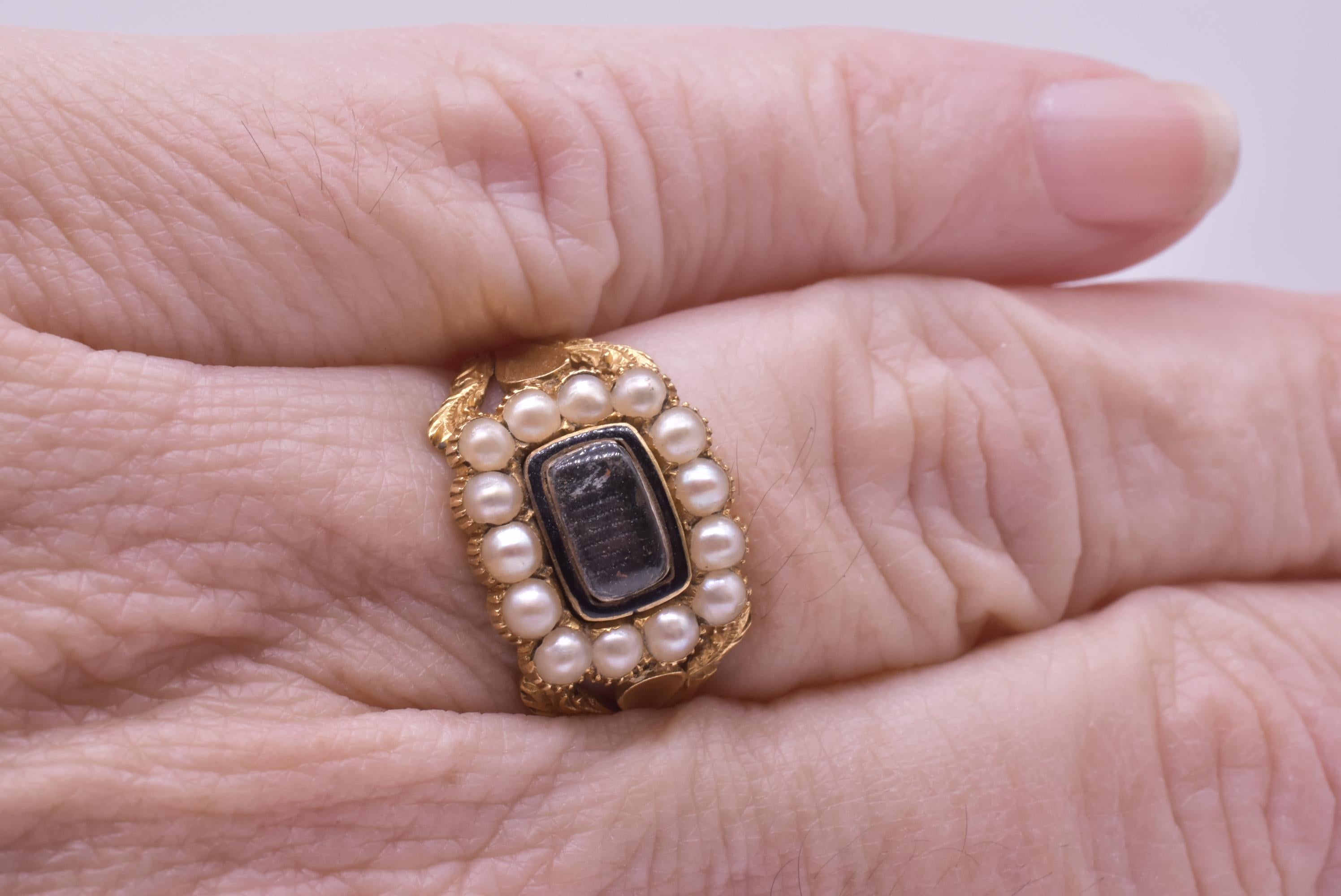 Lovely late Georgian 22 carat gold ring that is hallmarked Birmingham 1833. The ring has a surround of of natural split pearls around a rectangular beautifully enameled border in black that surrounds a plate of crystal which covers the beautiful