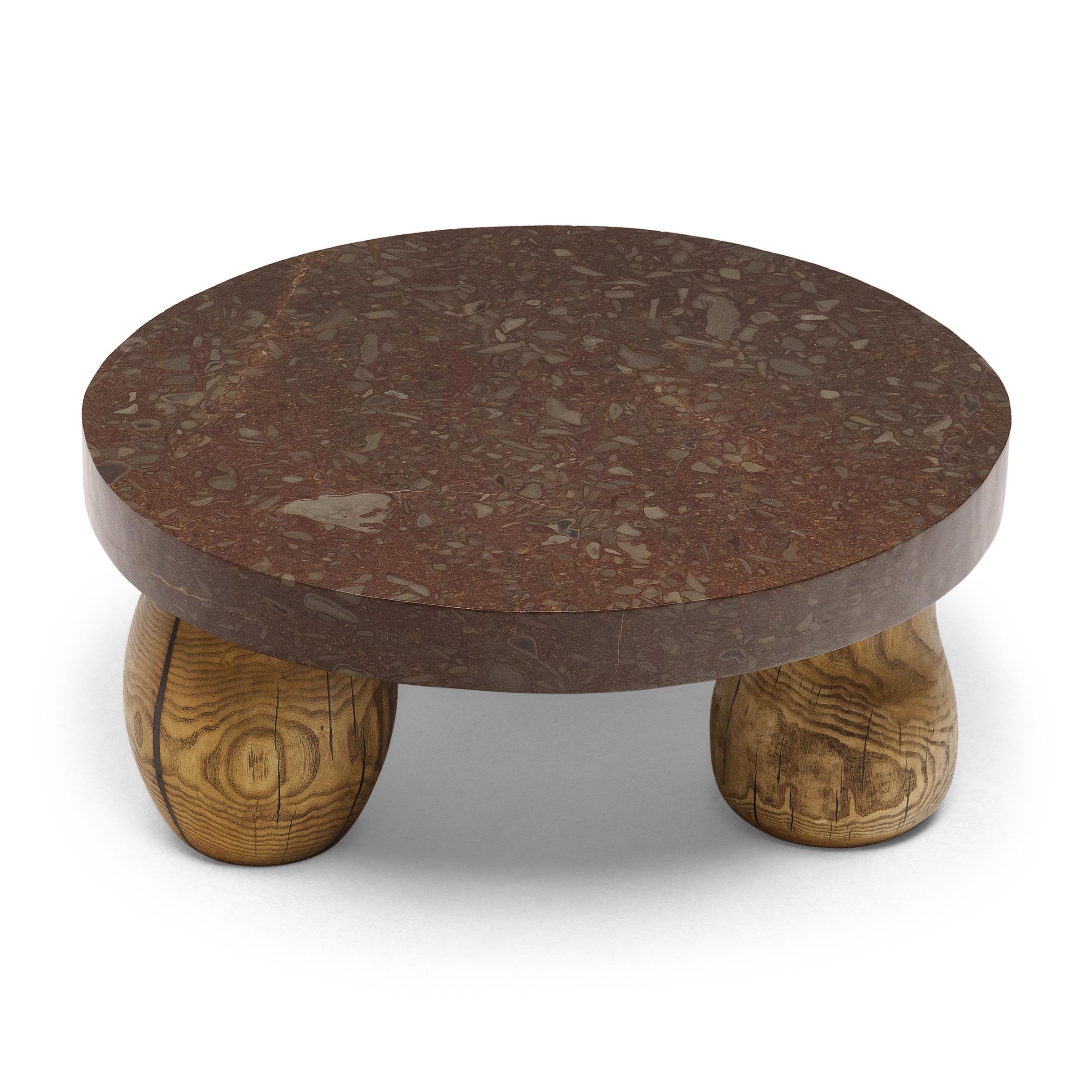 This stone top table exemplifies Organic Modern style with an emphasis on natural materials. The round stone top is carved from a unique material known as puddingstone, a conglomerate rock embedded with pebbles of various minerals. Named for its
