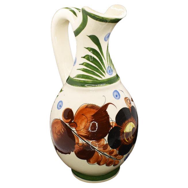 A beautiful example of traditional Mexican Folk Art, this pitcher will be a lovely addition to any table setting. Created from ceramic, it is glazed in a floral motif of green, blue, and maroon. 

Dimensions:
10.25