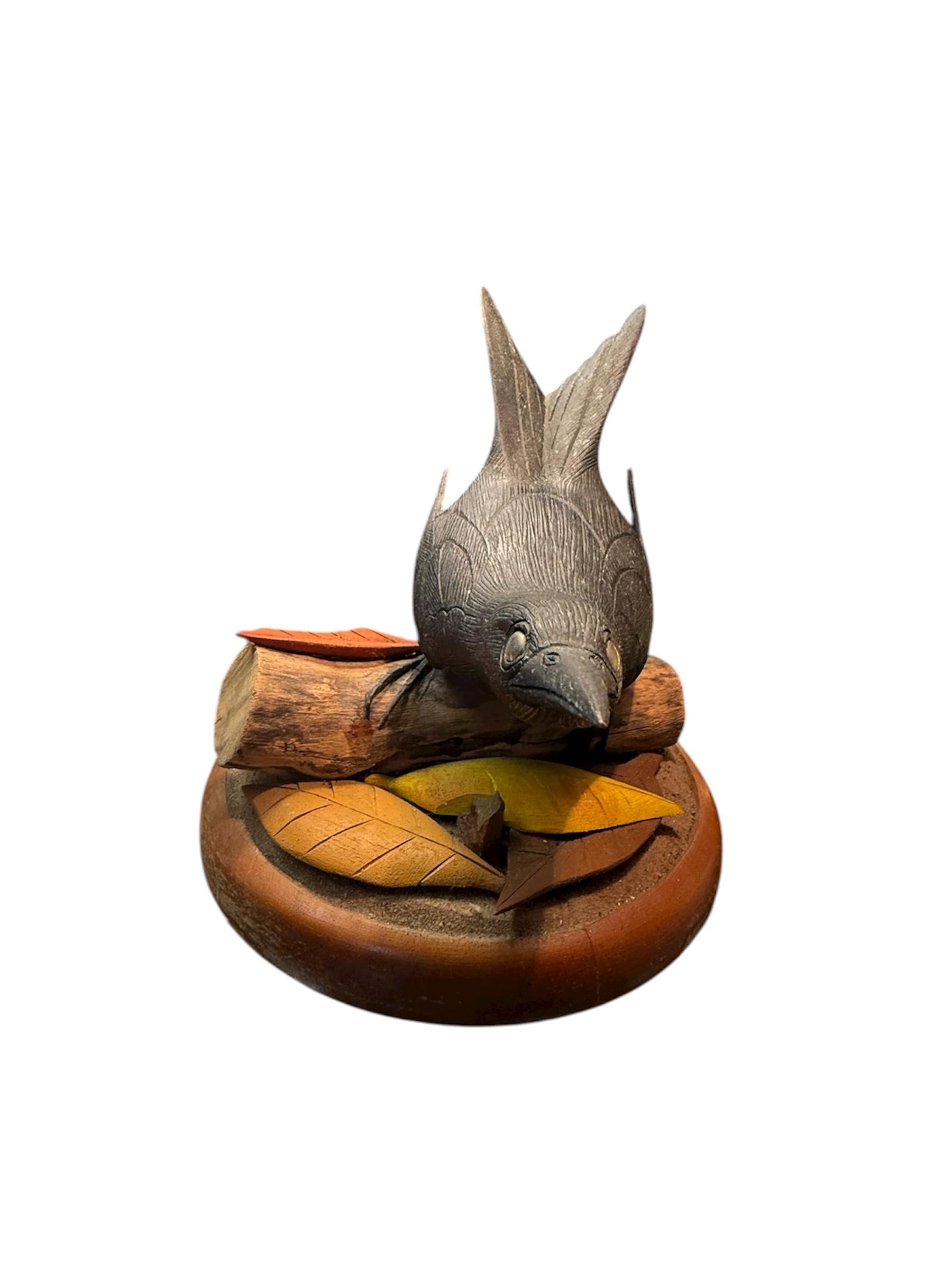 This is a Puerto Rican Hand Carved Bird Sculpture of a Greater Antillean Crackle-“Chango”. It depicts a well done hand carved black color bird with long wedge tail standing very alert in an original cut tree branch that is adorned with some autumn