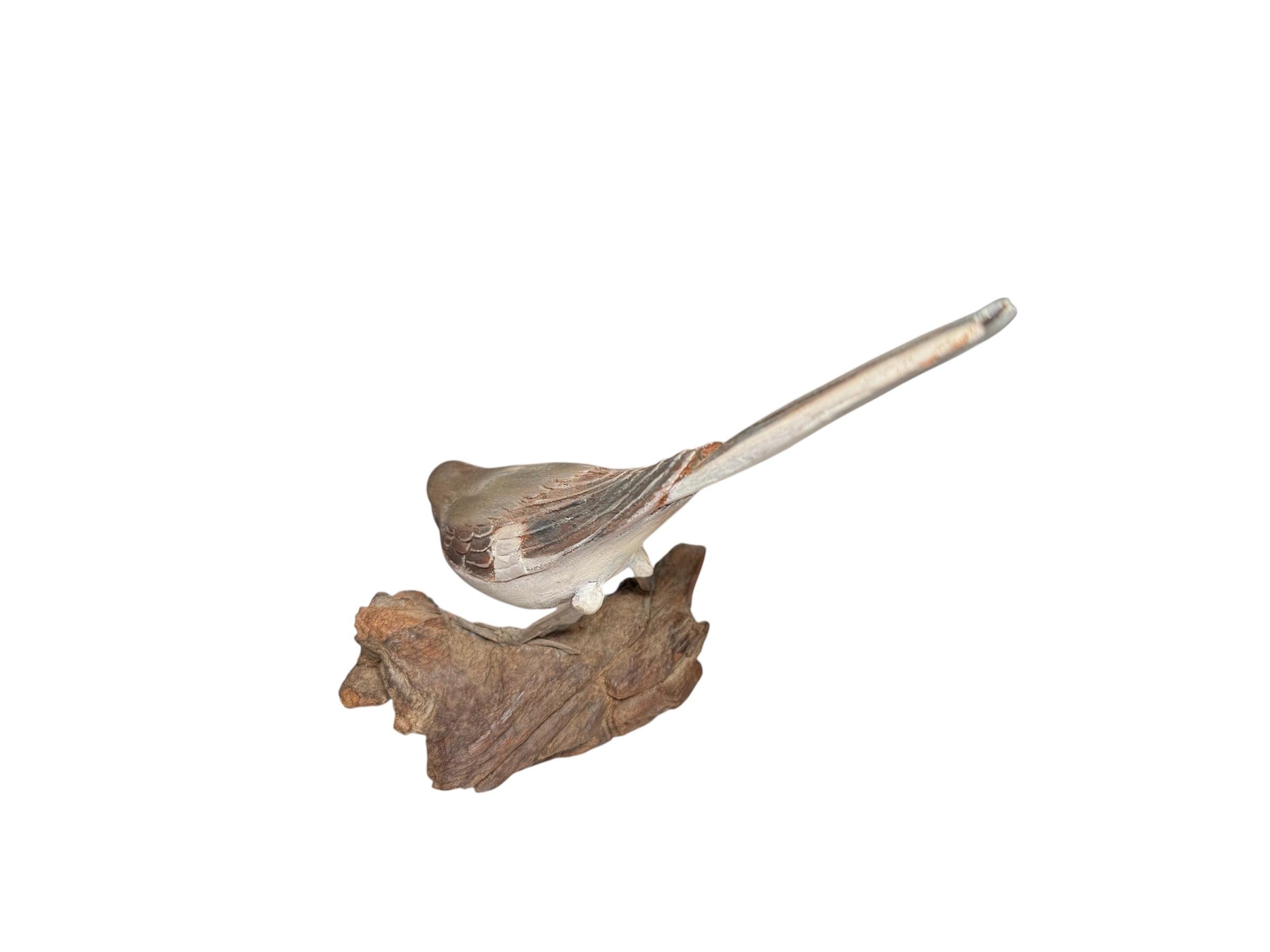 This is a Puerto Rican Hand Carved Wood Bird Sculpture. It depicts a beige, brown, grey and white bird sculpture of the so called Pearly- Eyed Thrasher standing on a wide cut piece of wood branch base. It is a very well done hand carving of this