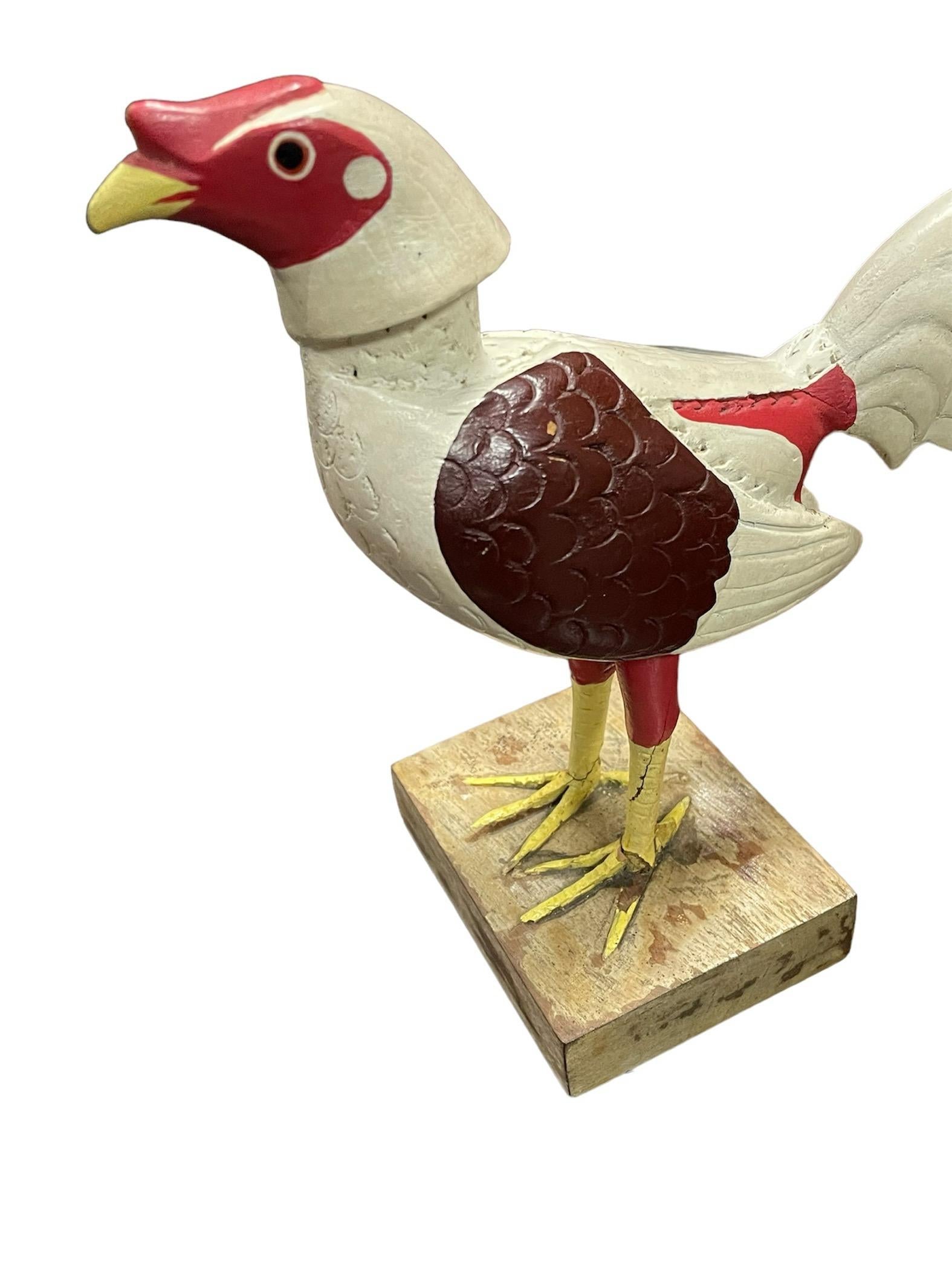 Dies ist ein Puerto Rican Hand Crafted Wood Rooster Sculpture von Emilio Rosado. Es zeigt einen handgeschnitzten und handbemalten weiß, rot, gelb und pflaumenfarben stehenden stolzen großen Hahn. Er steht auf einem quadratischen Holzsockel.