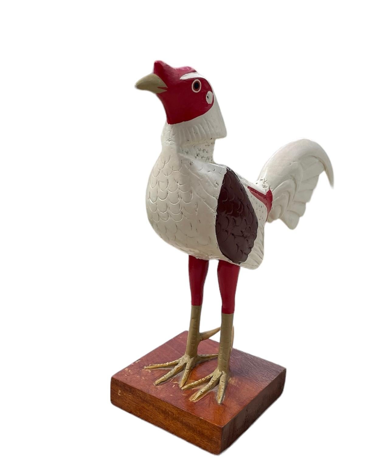 Dies ist ein Puerto Rican Hand Crafted Wood Rooster Sculpture von Emilio Rosado. Es zeigt einen handgeschnitzten und handbemalten weißen, roten, gelben und pflaumenfarbenen Hahn, der stolz und groß ist. Er steht auf einem quadratischen Holzsockel.