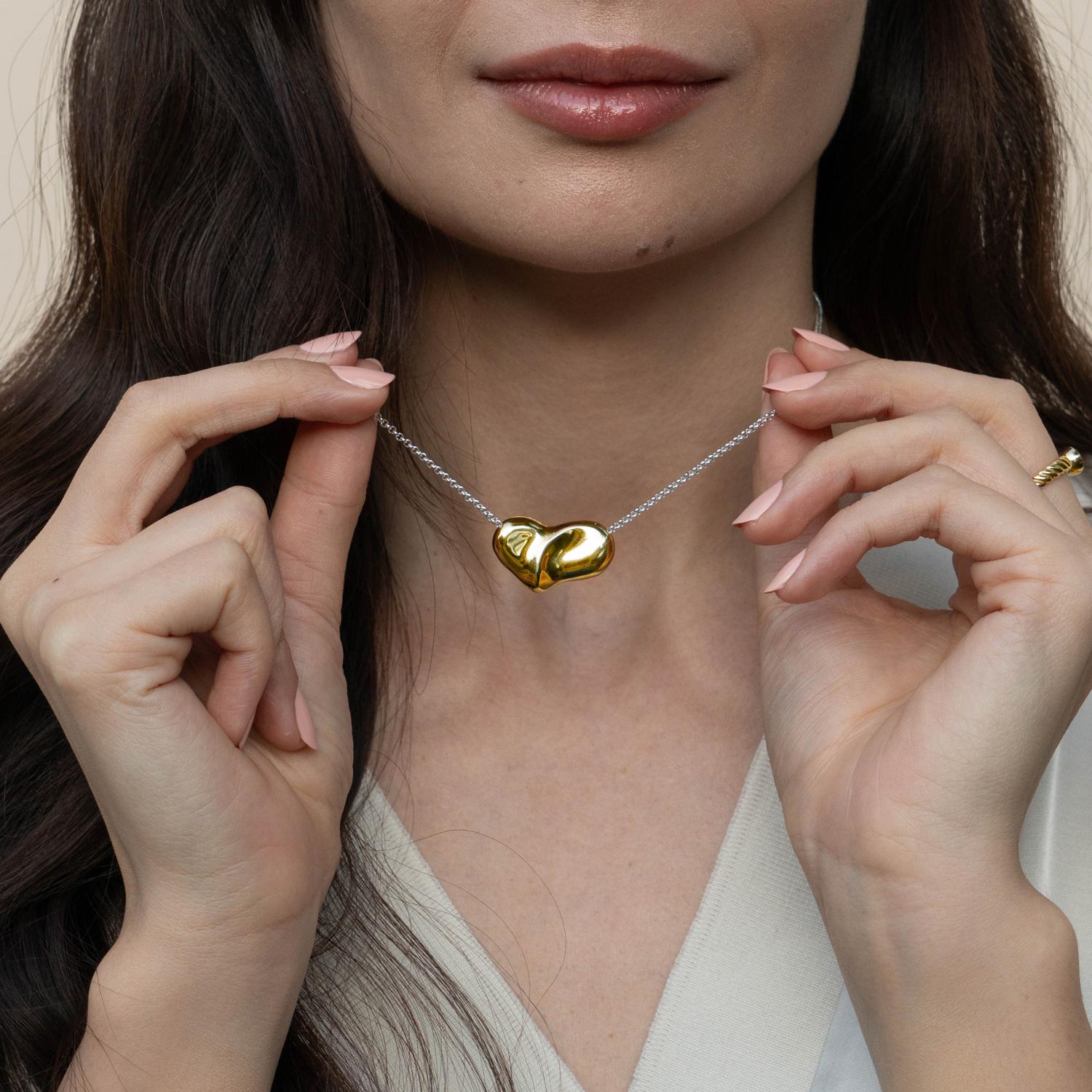 Realizzata in argento sterling con finitura in oro giallo vermeil, questa collana in metallo misto fatta a mano presenta un cuore scolpito a forma di soffio che cattura l'essenza dell'amore. Il cuore è sospeso su una raffinata catena belcher,