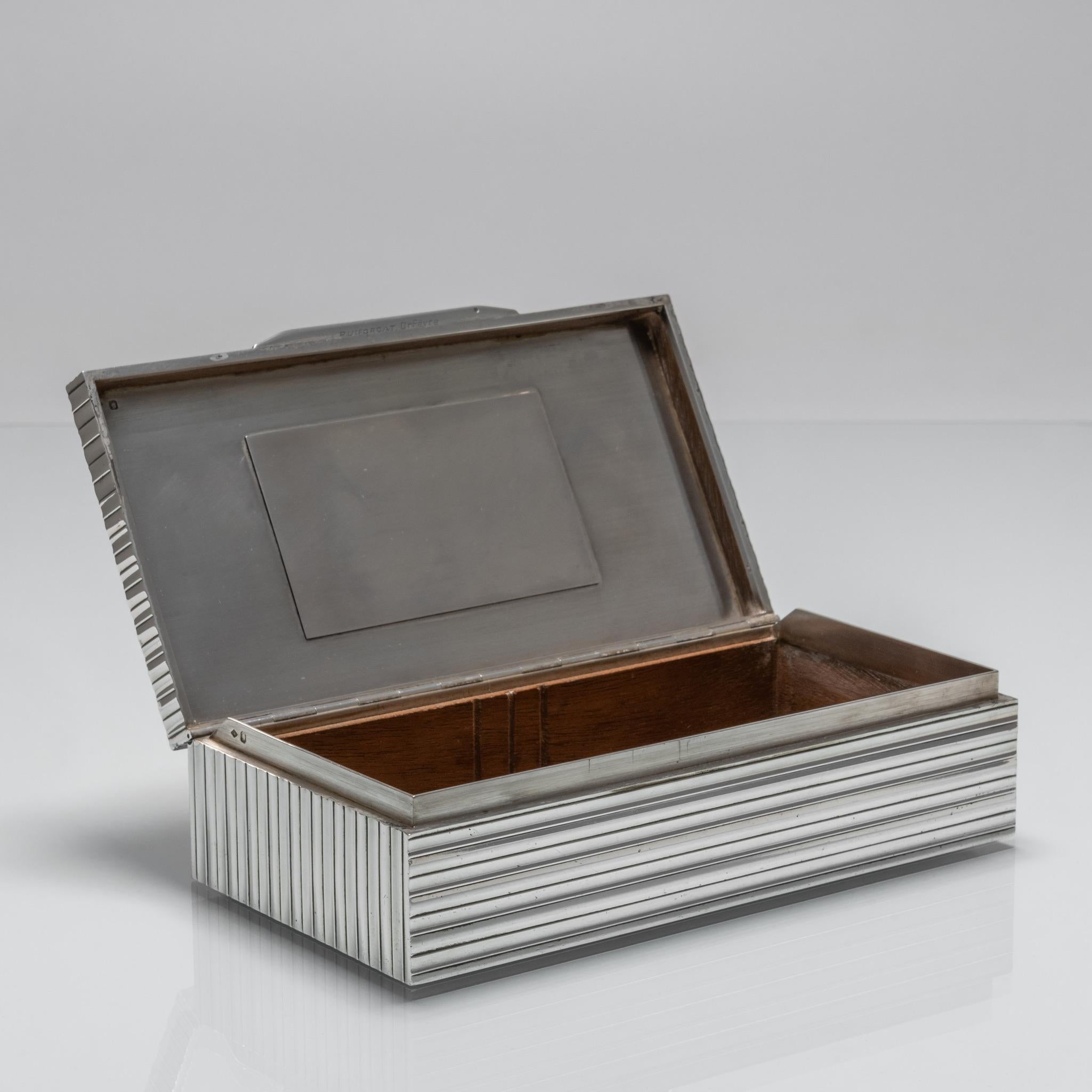 A stylish cigarette box in reeded silver with cedar lining by Jean Emile Puiforcat (1897-1945), French Art Deco silversmith, sculptor and designer.

Dimensions: 18cm/7 inches (length) x 9.5cm/3¾ inches (depth) x 4.5cm/1¼ inches (height).

Bentleys