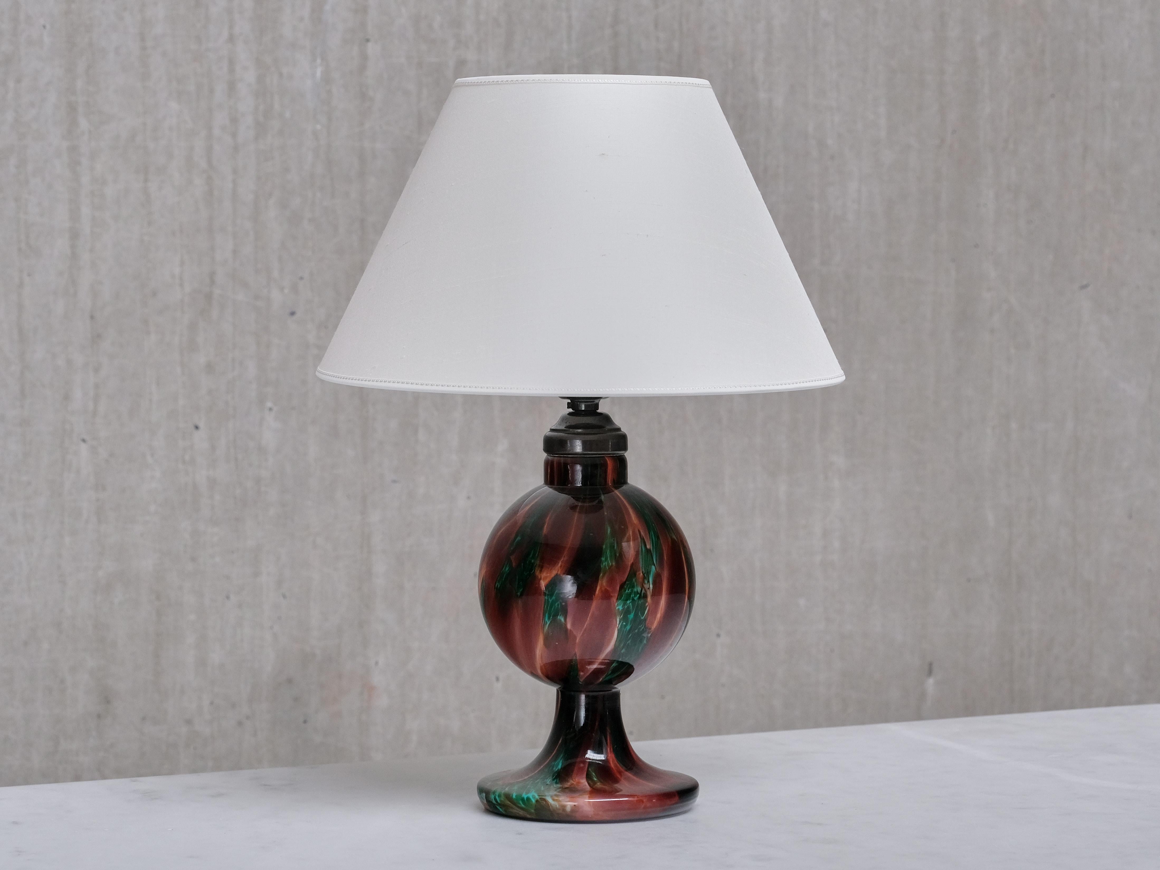 This rare table lamp was produced by Böhlmarks in Sweden in the 1920s, with the glass base crafted at Pukebergs Glasbruk, which was owned by Böhlmarks at the time. This series of marbled glassware is documented in Böhlmarks' 1925 catalogue.

The