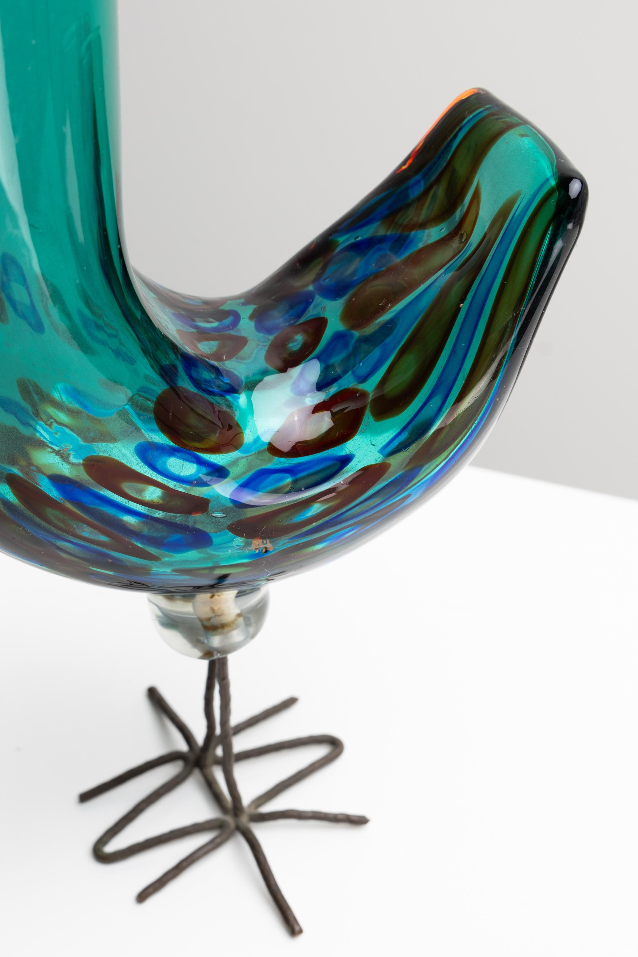 Sculpture d'un oiseau en verre soufflé à décor de murrine, reposant sur des pieds en cuivre martelé. Conçu en 1962 par Alessandro Pianon pour Vistosi, Murano (Italie).
Cet oiseau en verre vert a un corps orné de murrines rouges et bleues, y compris