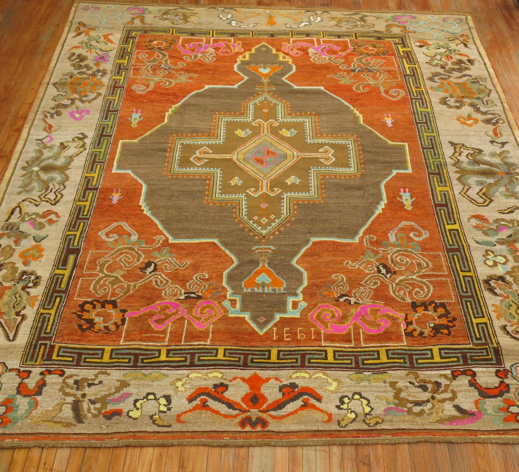 Pumpkin Orange color 20th century Turkish Kars square size rug with a large graphic brown medallion surrounding 4 people and a large scale gray floral border. Is it Masculine or Feminine? You can say its both. Measures 10'9'' x 12'9'' dated 1931.