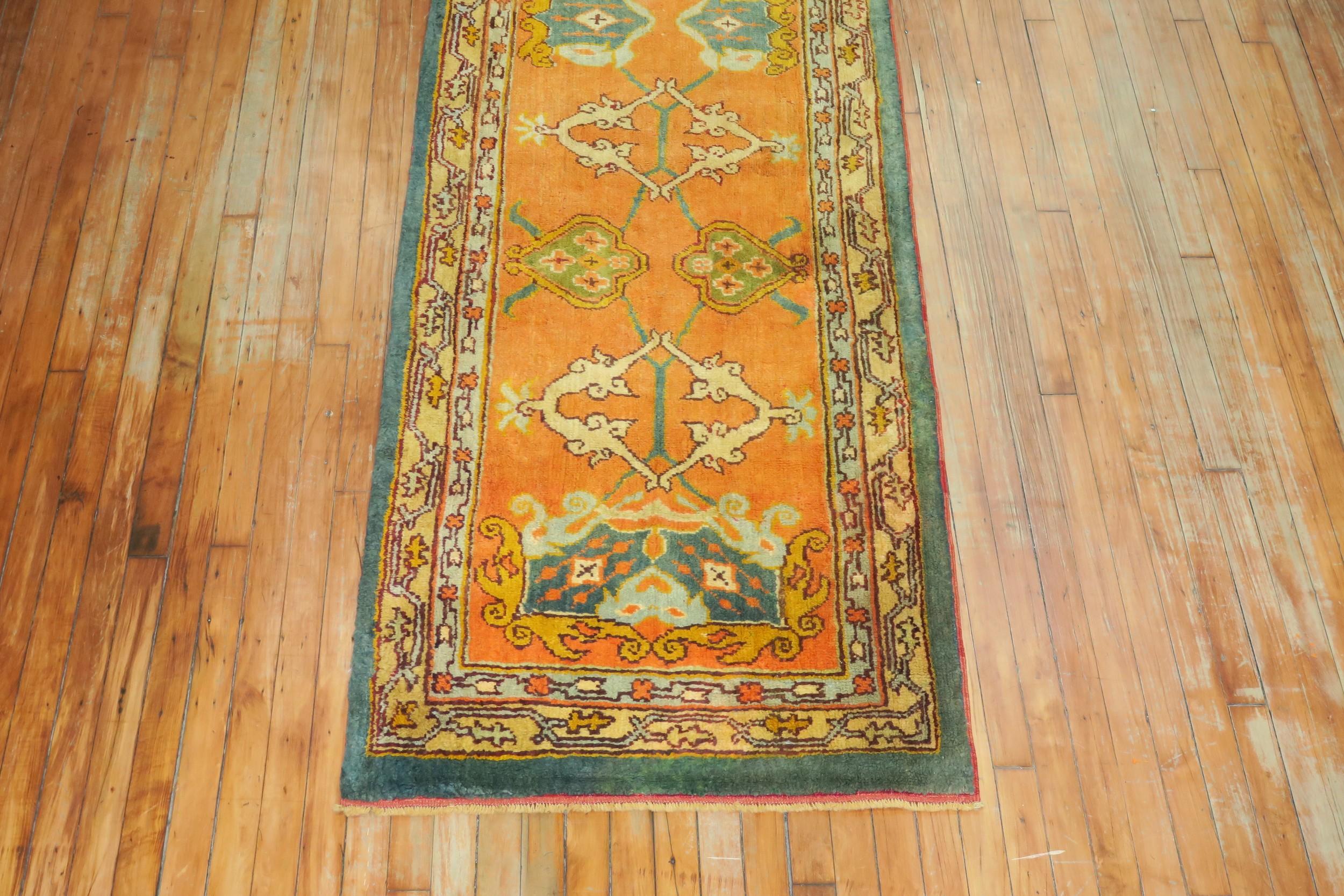 An early 20th century antique Oushak runner featuring a pumpkin orange field, forest green border with an all-over design attributed to the Arts & Crafts movement.

Measures: 2'10” x 15'8”.