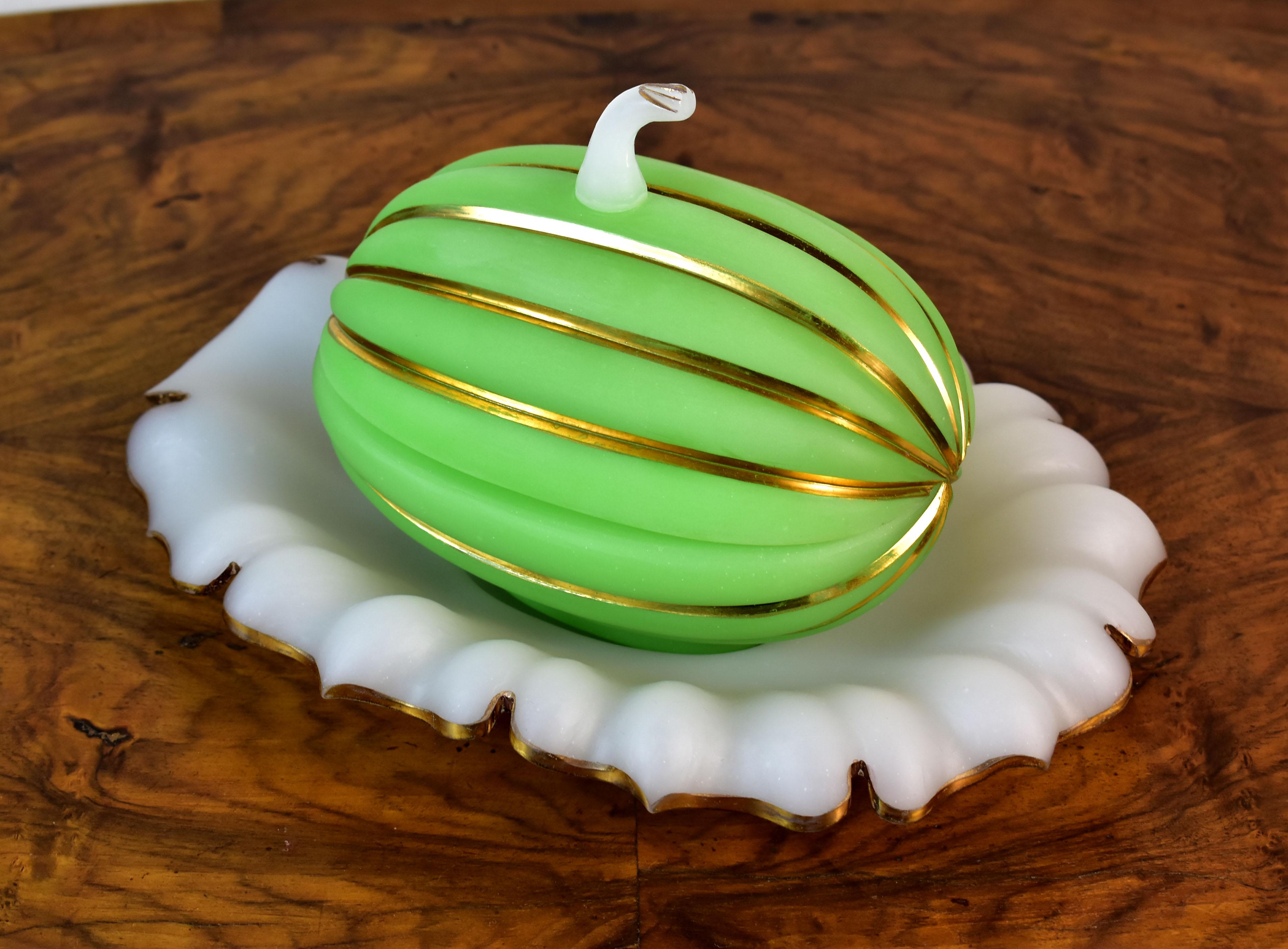 A beautiful and very interesting jar with a plate made of opaline glass in the shape of a pumpkin. The pumpkin-shaped jar is made of green opaline with a chip of white, all completed with gold painting. The plate is in the shape of a leaf, made of