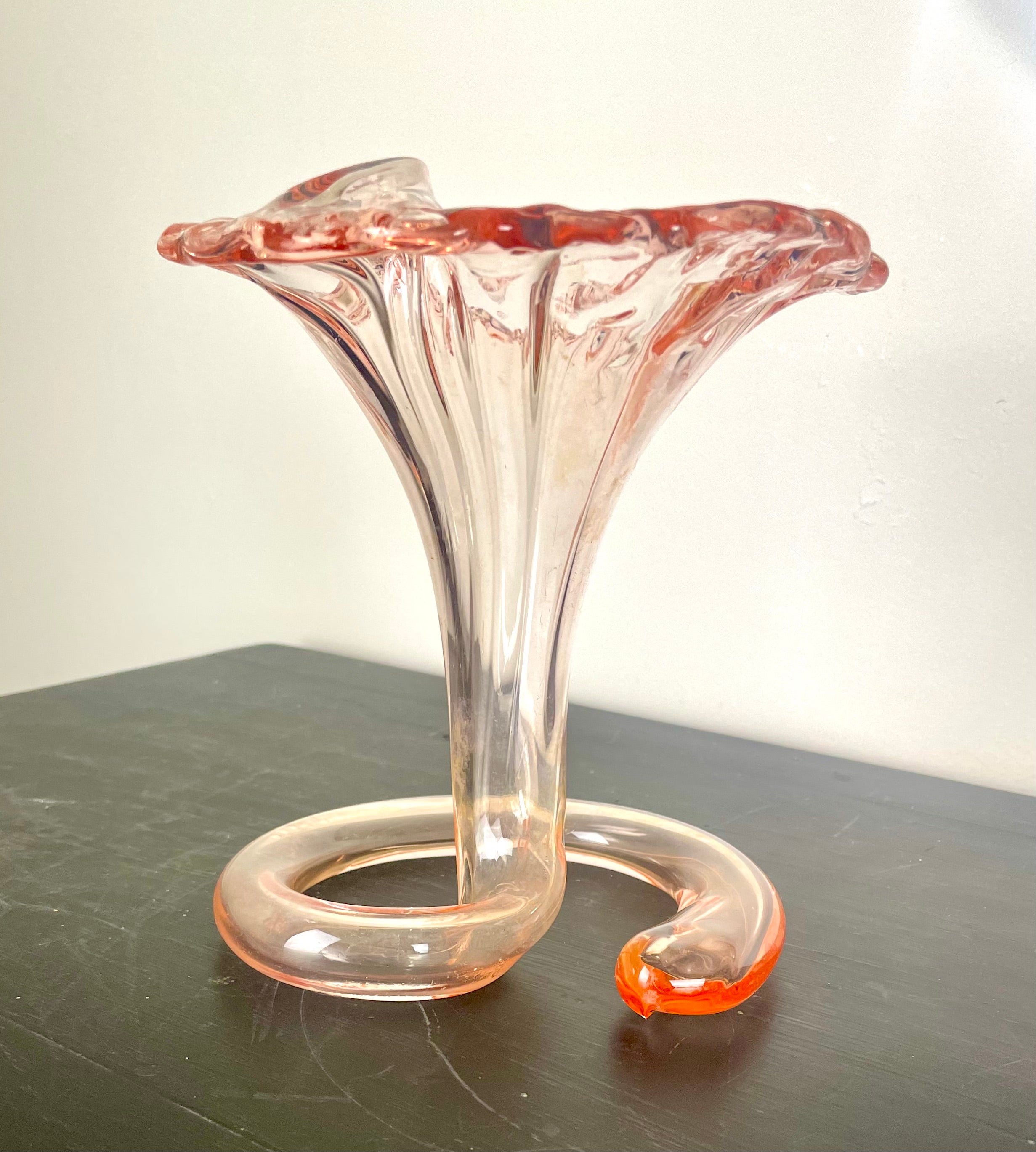 Elegant trumpet vase for flowers in blown glass with spiral base.
Blown glass forms a stylized trumpet fleur de lys resting on a spiral coil base.
Textured glass surface around the wide rim.
The spiral base is hollow and also retains water when