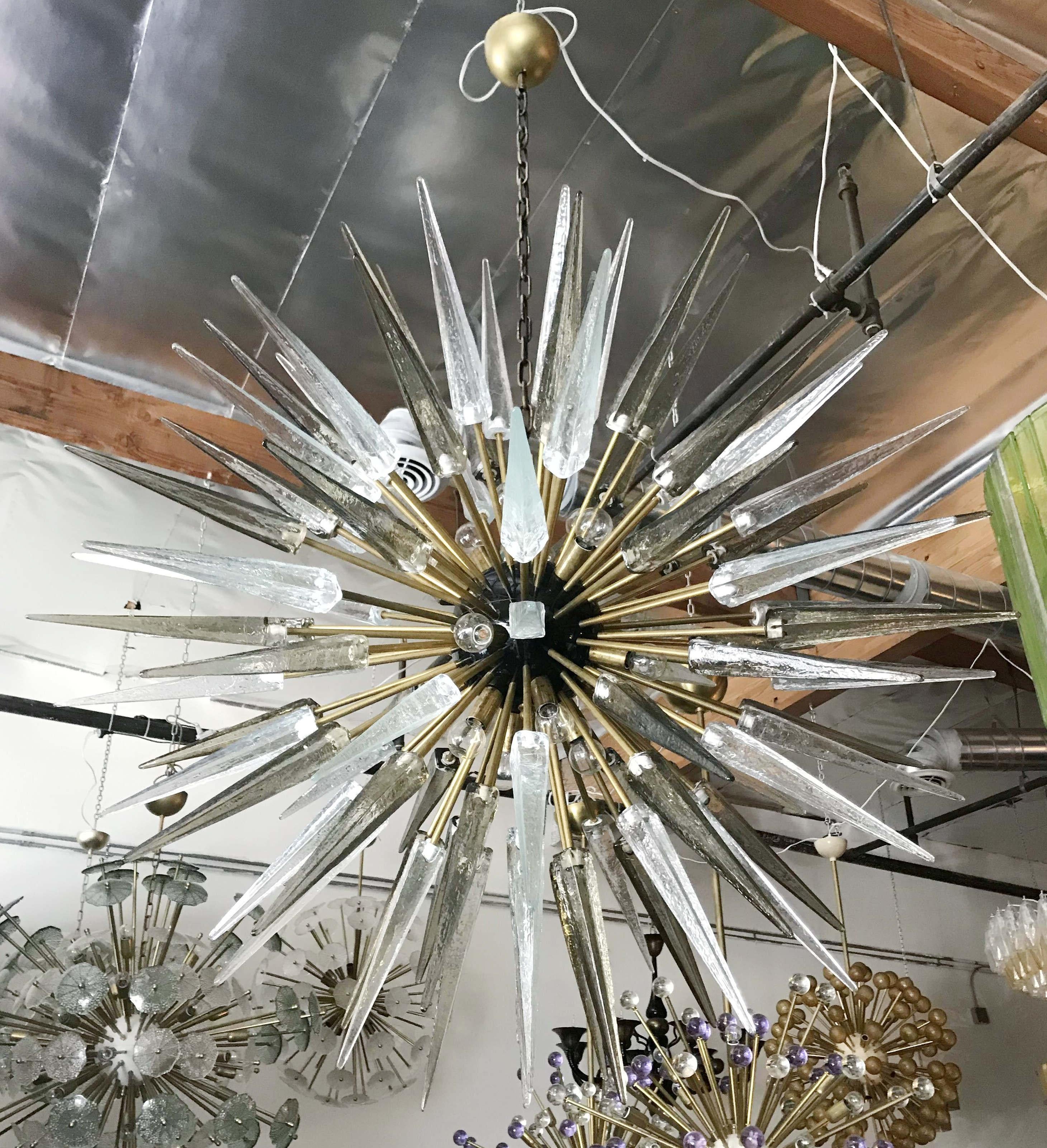 Italian modern Sputnik chandelier with clear and smoky Murano glass shards spikes, mounted on natural unlacquered brass frame with black enameled centre, designed by Fabio Bergomi for Fabio Ltd, made in Italy
16-light / E12 or E14 type / max 40W