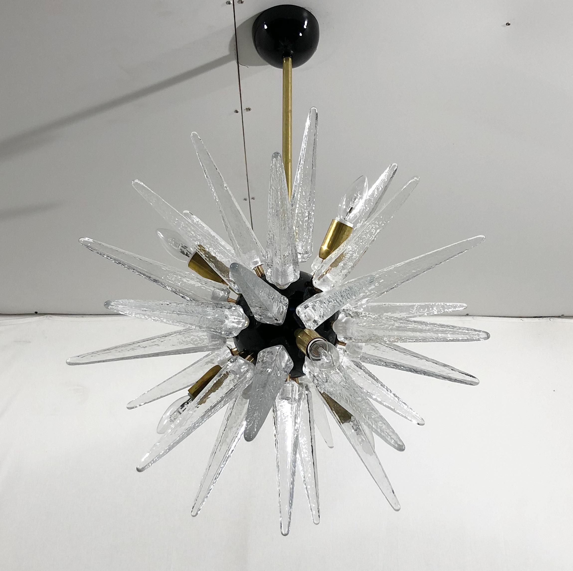 Lampadario Sputnik moderno italiano con punte in vetro di murano trasparente, montato su una struttura in ottone naturale non laccato con centro e baldacchino nero lucido, disegnato da Fabio Bergomi per Fabio Ltd / Made in Italy
6 luci / tipo E12 o