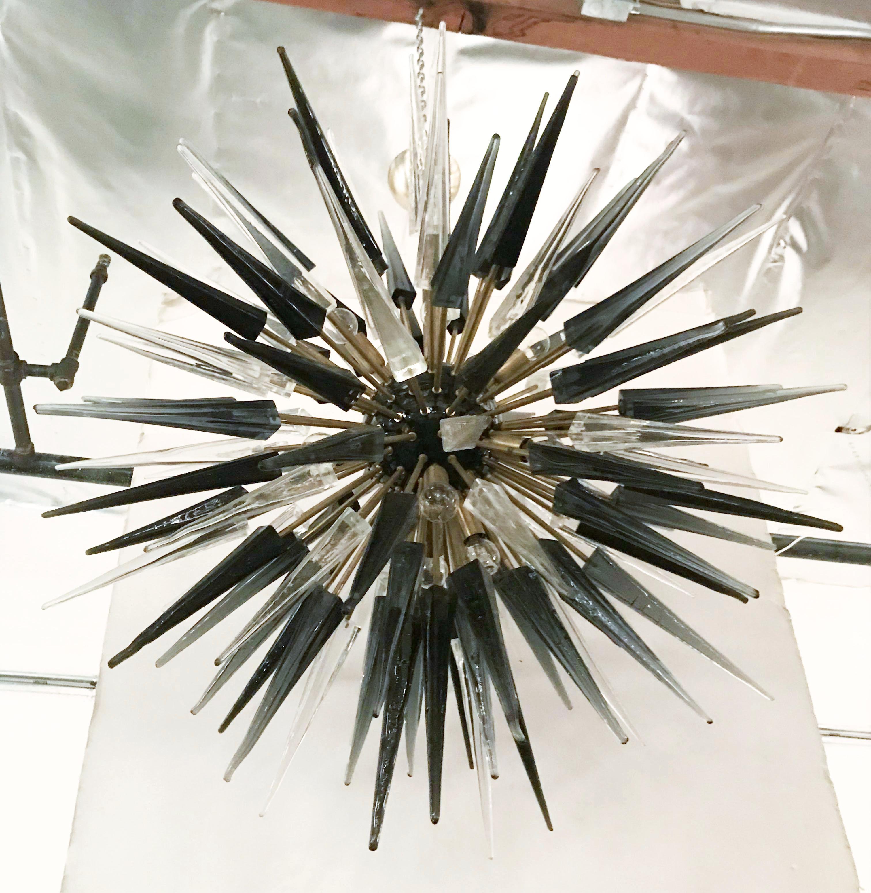 Italian Sputnik chandelier with clear, smoky and black Murano glass shards on bronzed brass metal frame and enamled black center / Designed by Fabio Bergomi for Fabio Ltd / Made in Italy
12 lights / E14 type / max 40W each
Diameter: 42 inches /