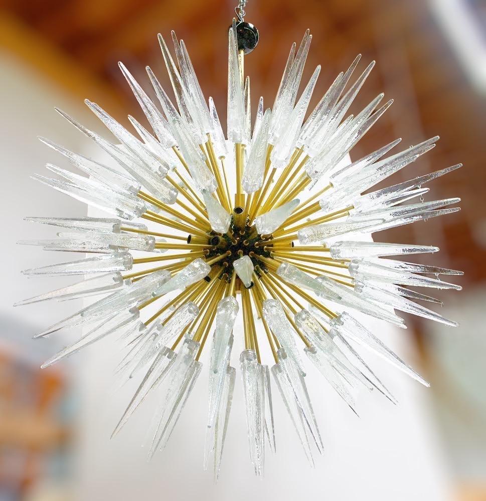 Lustre Sputnik moderne italien avec des pointes en verre de Murano clair, monté sur une monture en laiton naturel non laqué avec centre émaillé noir, conçu par Fabio Bergomi pour FABIO LTD / Fabriqué en Italie
16 lampes / Type E12 ou E14 / Max 40W