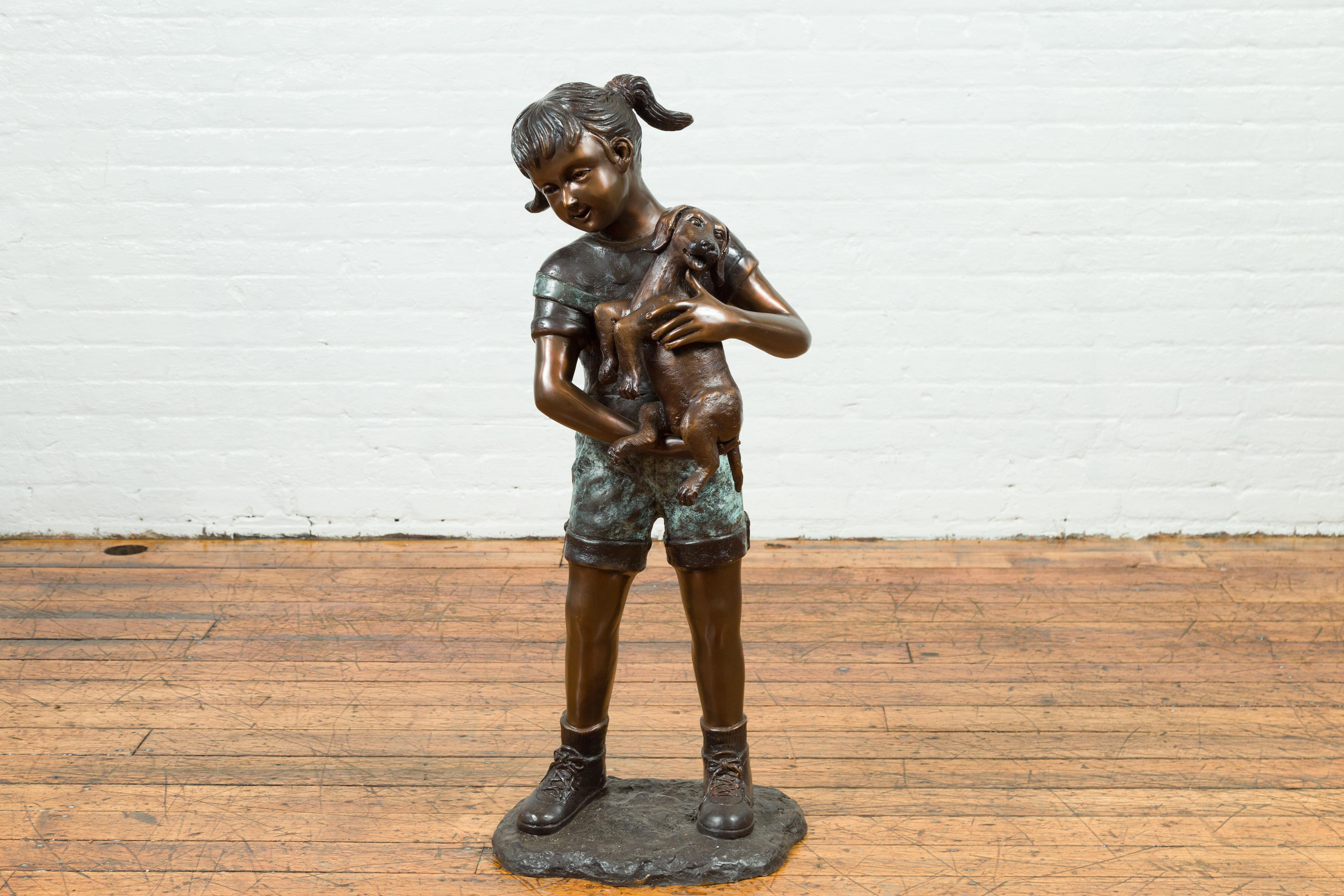'Puppy Kisses', a contemporary bronze sculpted group depicting a little girl holding her puppy in her arms. Cast with the traditional technique of the lost-wax (à la cire perdue) allowing great precision and finesse in the details, this sculpted