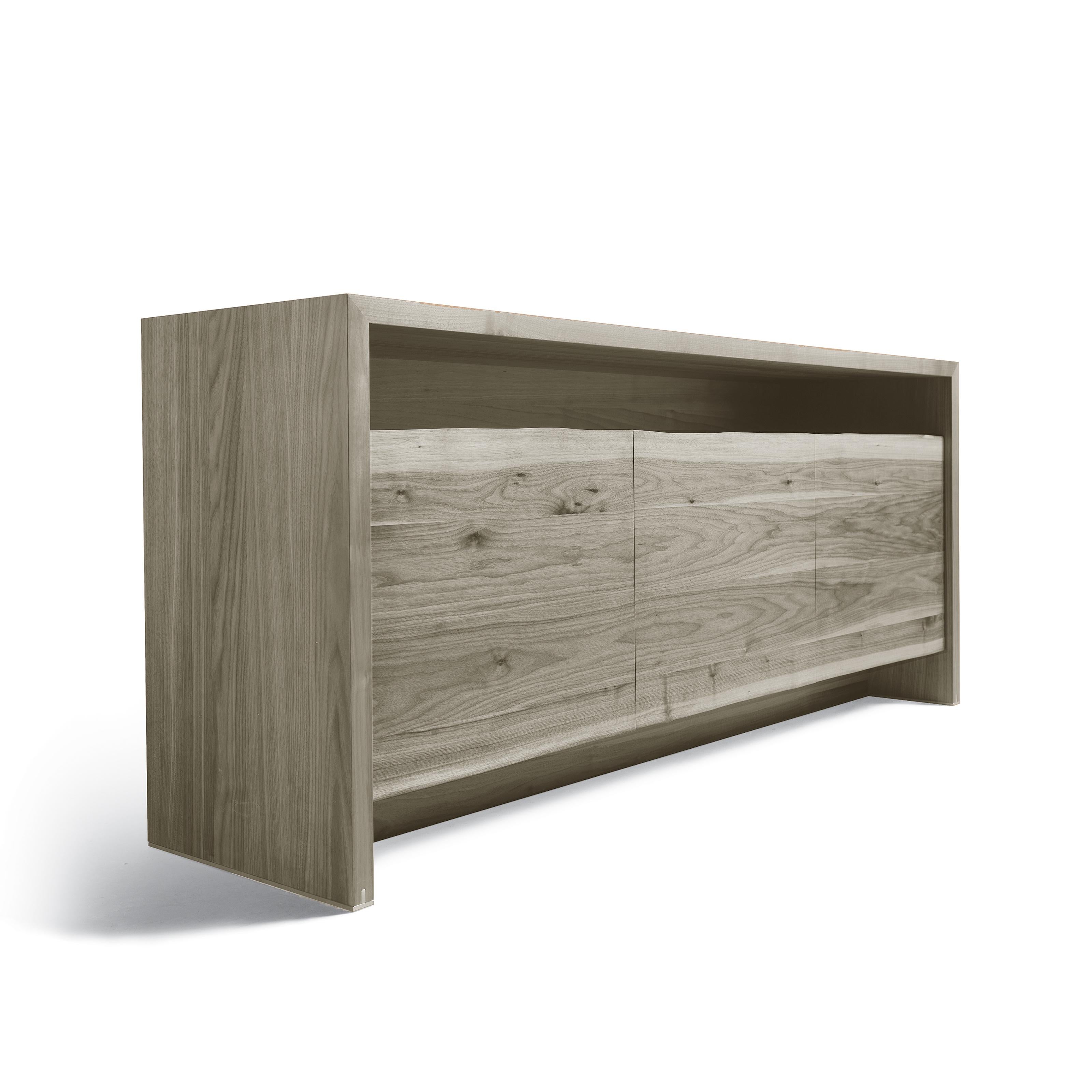 Handcrafted in Italy with passion and expertise, the Puraforma solid wood sideboard combines aesthetic solutions with a sophisticated design. The doors in debarked wood highlight the oblique cut through the chromatic difference of the walnut